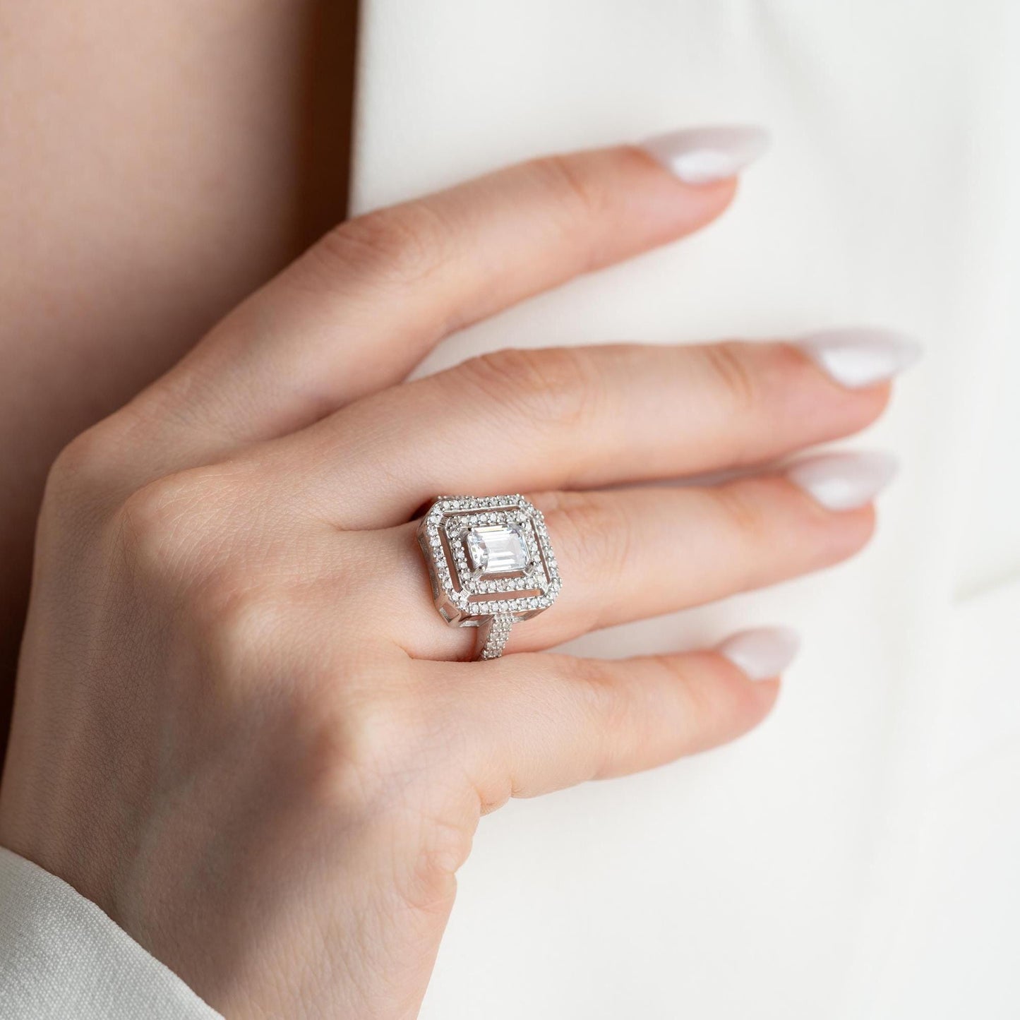 Elegant emerald cut double halo statement ring crafted in 925 sterling silver with cubic zirconia stones, available in silver and gold plated finishes.