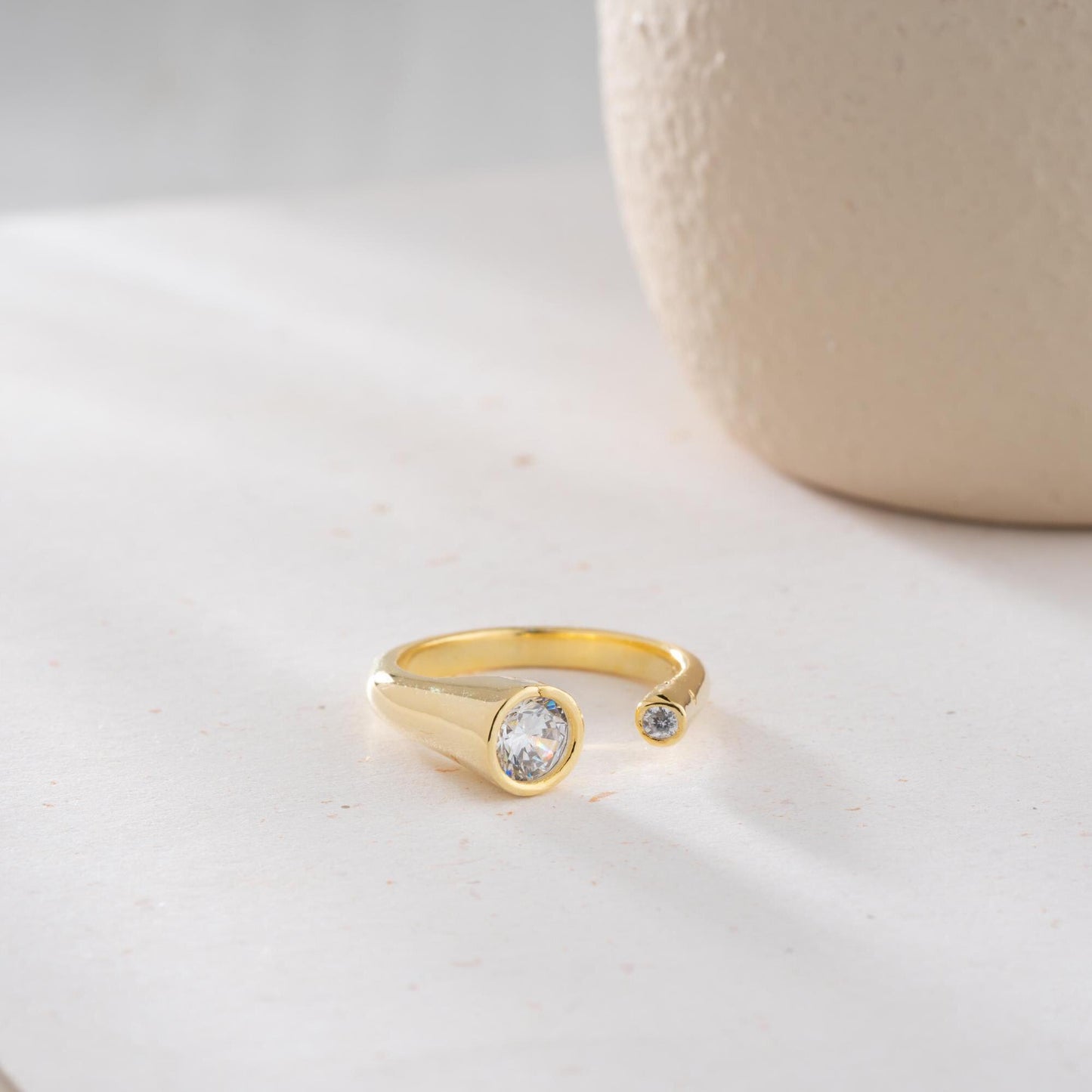 Elegant open ring with dual bezel-set zircon stones, crafted from 925 sterling silver and available in gold plated and silver finishes.