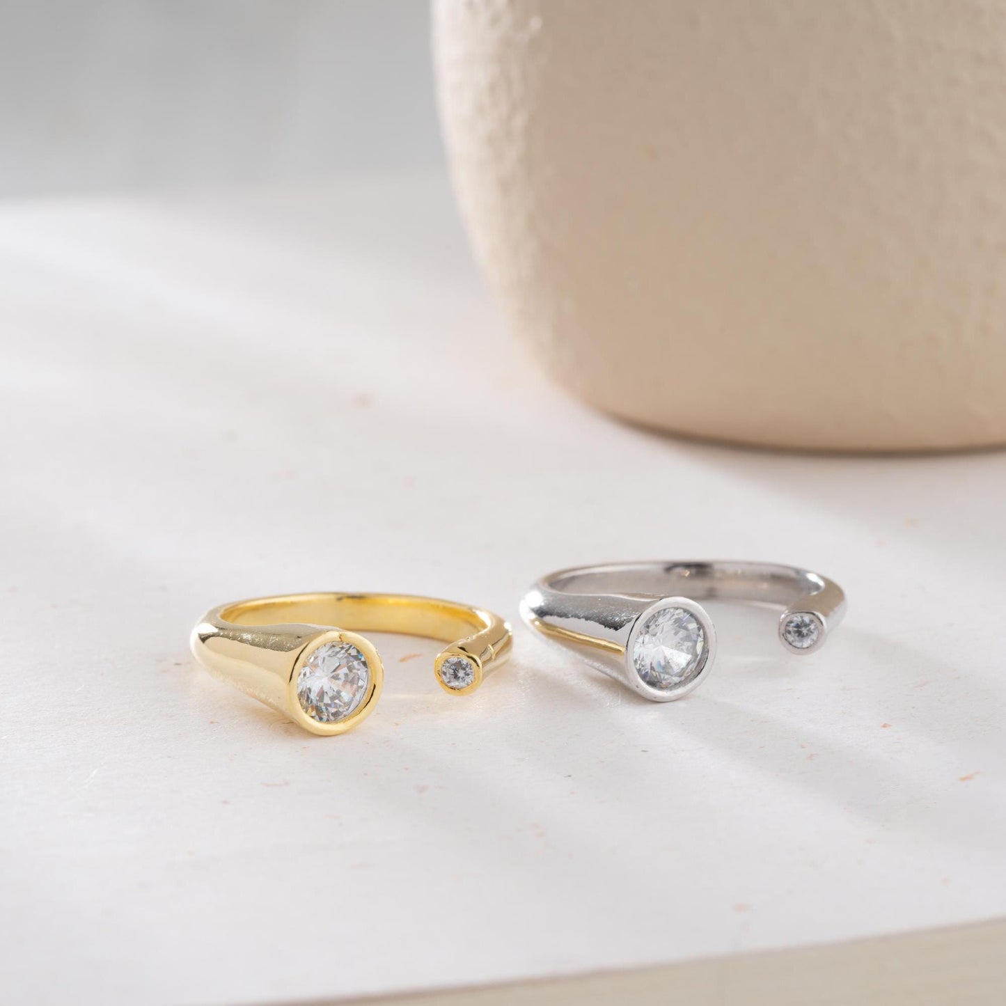 Elegant open ring with dual bezel-set zircon stones, crafted from 925 sterling silver and available in gold plated and silver finishes.
