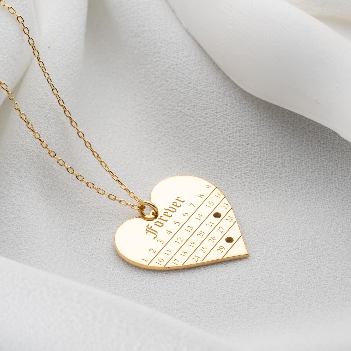 A personalized heart-shaped calendar necklace with a custom date engraving, available in sterling silver and gold plated finishes. Perfect for anniversaries, weddings, or Valentine's Day.