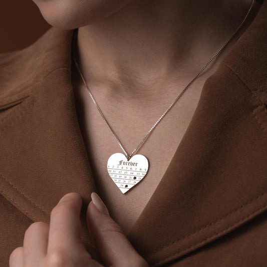 A personalized heart-shaped calendar necklace with a custom date engraving, available in sterling silver and gold plated finishes. Perfect for anniversaries, weddings, or Valentine's Day.