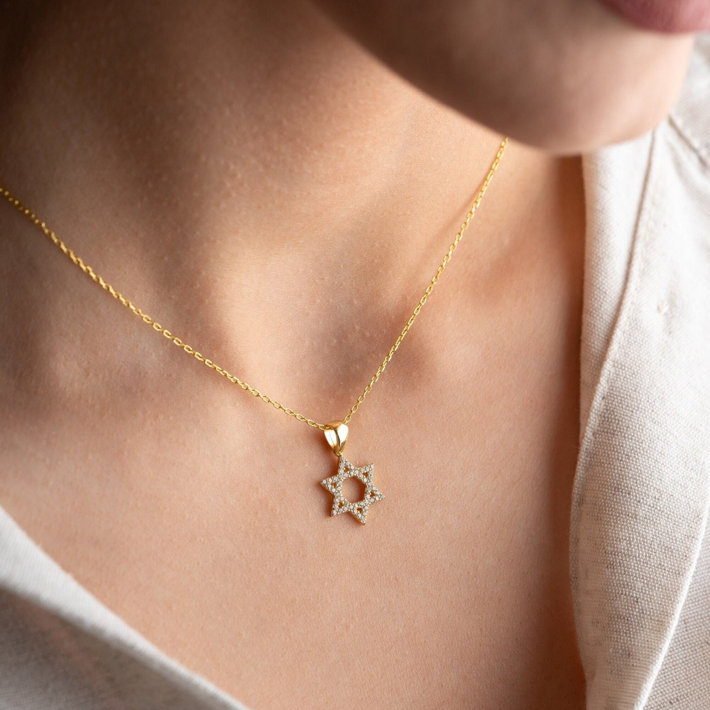 Close-up of a sparkling zircon-embellished Star of David pendant made of 925 sterling silver against a soft white background.