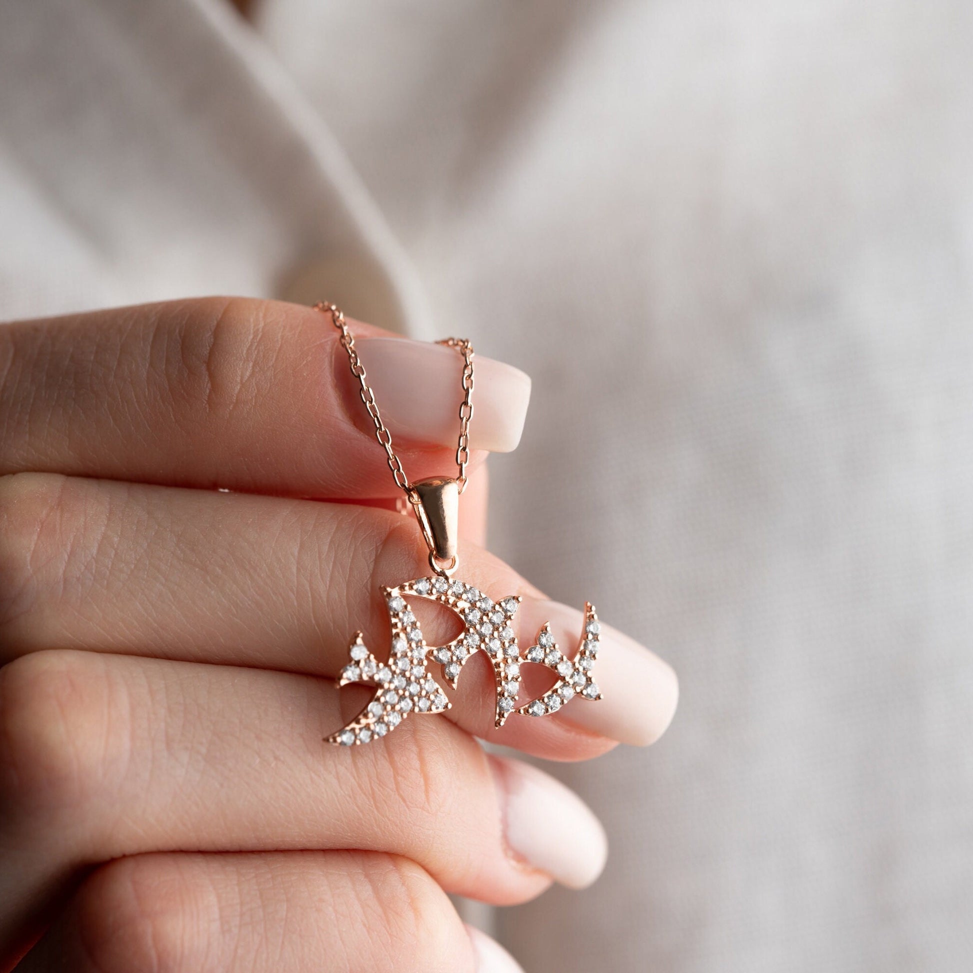 Elegant three seagulls silver necklace with sparkling zircon gemstones detail on a light background.