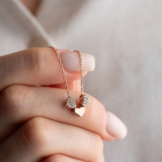 An exquisite silver necklace featuring three interlocking hearts, each heart intricately detailed with sparkling zircon stones, creating a luxurious and romantic piece perfect for gifting on special occasions or expressing love and affection.