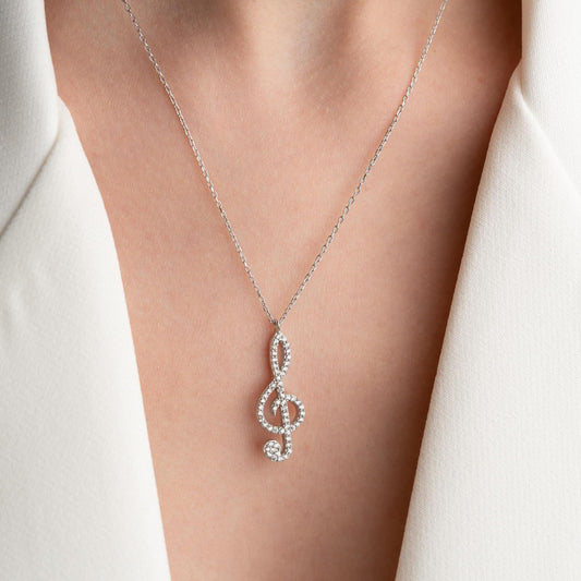 Music note necklace with cubic zirconia stones, available in 925 sterling silver and 14K gold plated options, displayed on a white satin background.