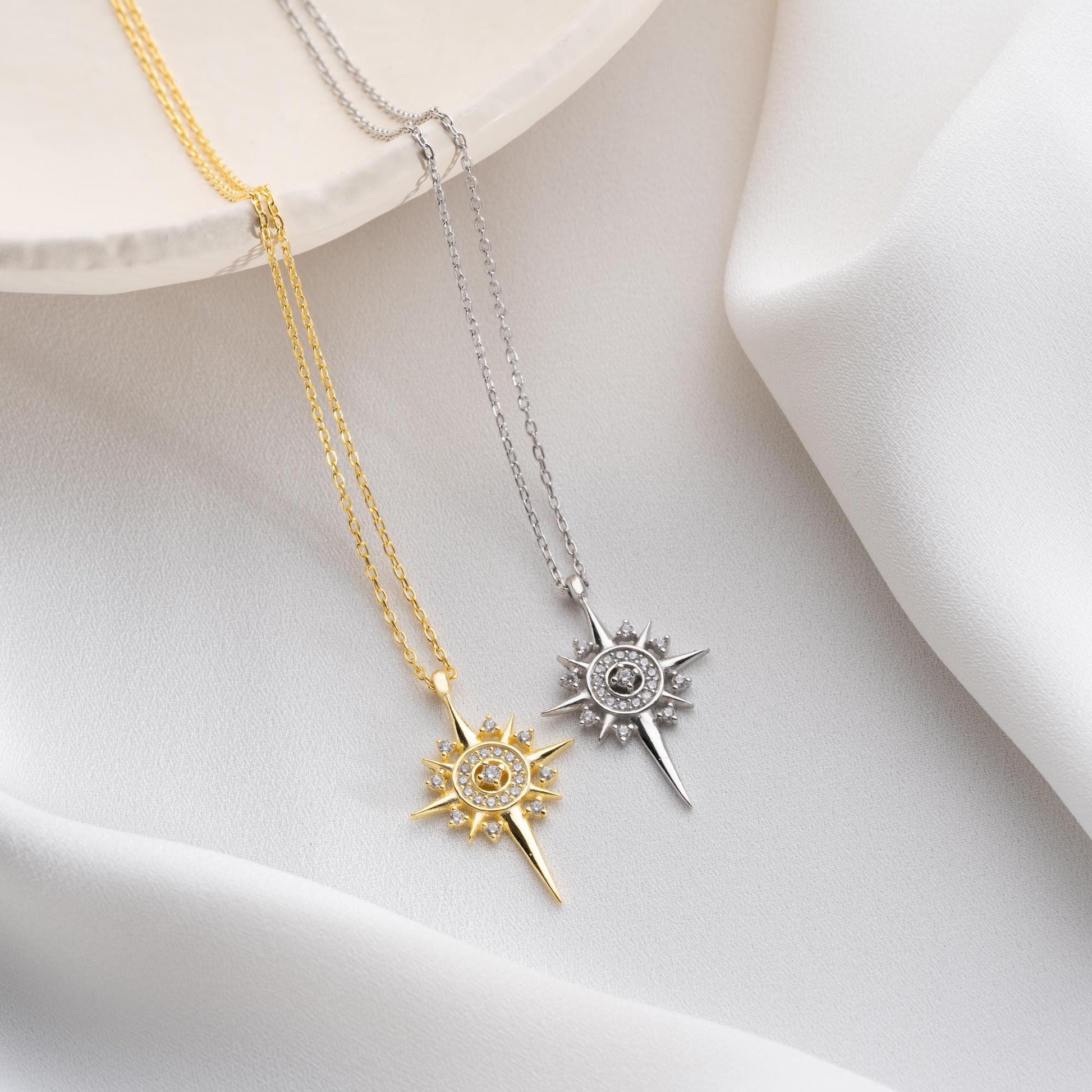 Sun and star necklace with cubic zirconia stones, available in 925 sterling silver and 14K gold plated options, displayed on a white satin background.