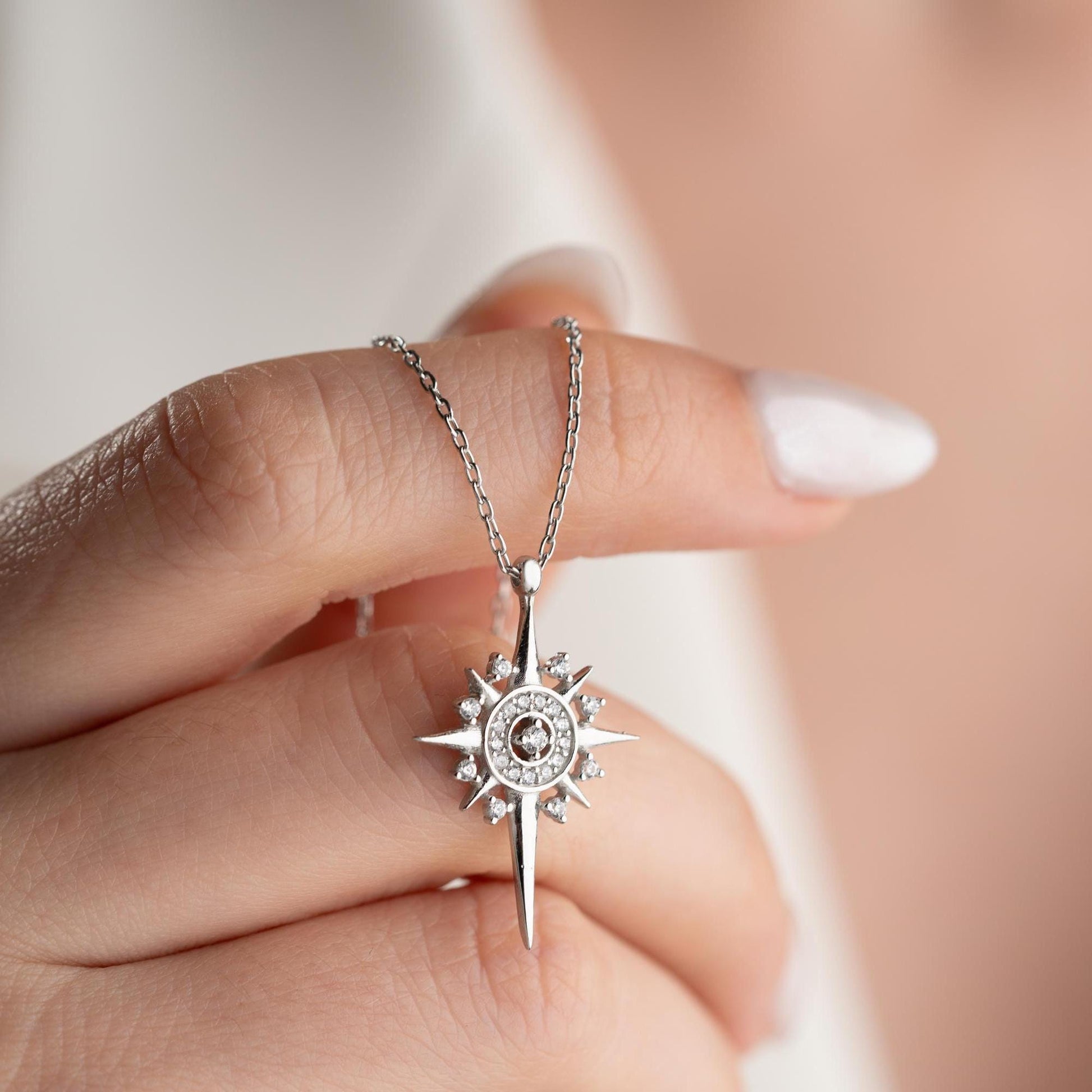 Sun and star necklace with cubic zirconia stones, available in 925 sterling silver and 14K gold plated options, displayed on a white satin background.