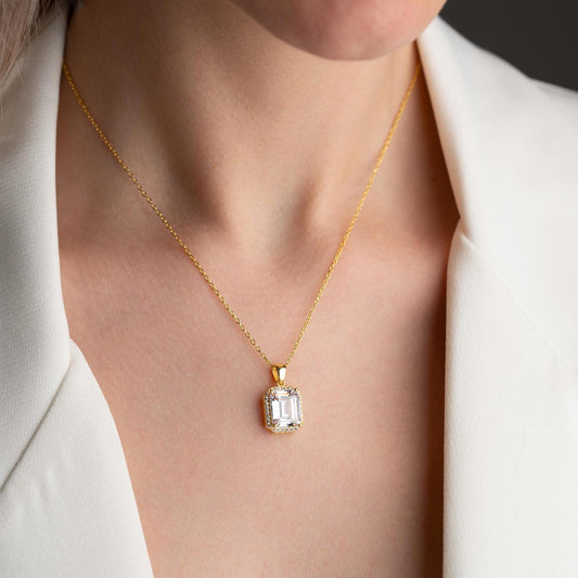 Emerald-cut pendant necklace with cubic zirconia stones, available in 925 sterling silver and 14K gold plated options, displayed on a white satin background.