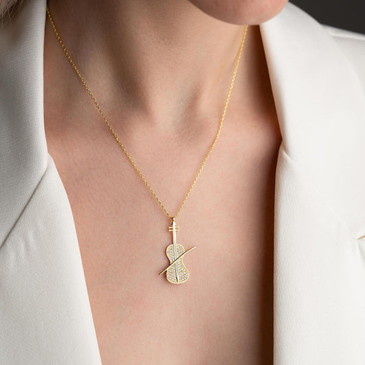 Violin-shaped necklace with cubic zirconia stones, available in 925 sterling silver and 14K gold plated options, displayed on a white satin background.