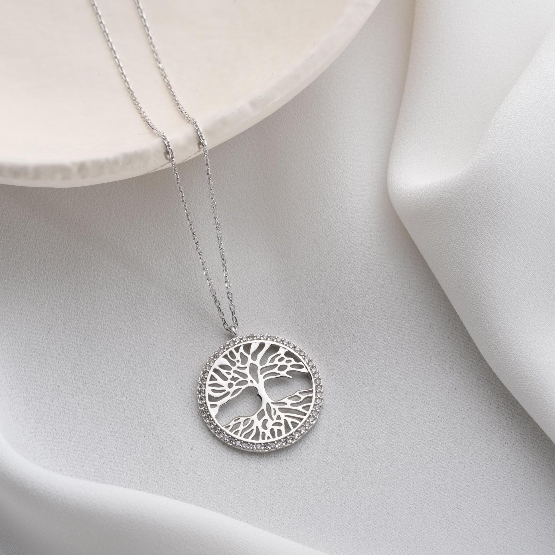 Tree of Life necklace with cubic zirconia stones, available in 925 sterling silver and 14K gold plated options, displayed on a white satin background.