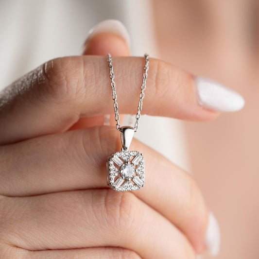 Square pendant necklace with cubic zirconia stones, available in 925 sterling silver and 14K gold plated options, displayed on a white satin background