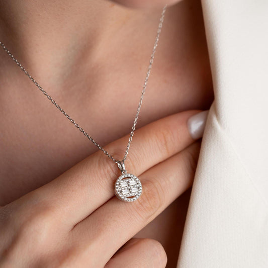 Round pendant necklace with cubic zirconia stones, available in 925 sterling silver and 14K gold plated options, displayed on a white satin background.