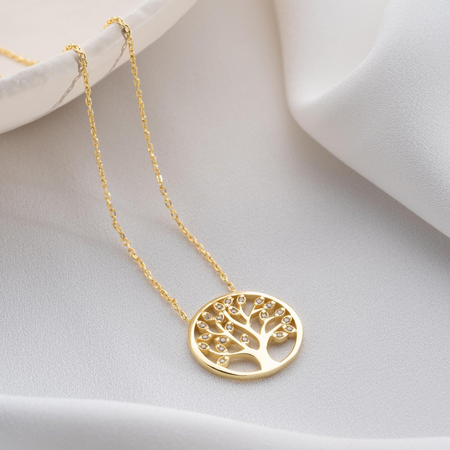 Tree of Life pendant necklace with cubic zirconia stones, available in 925 sterling silver and 14K gold plated options, displayed on a white satin background