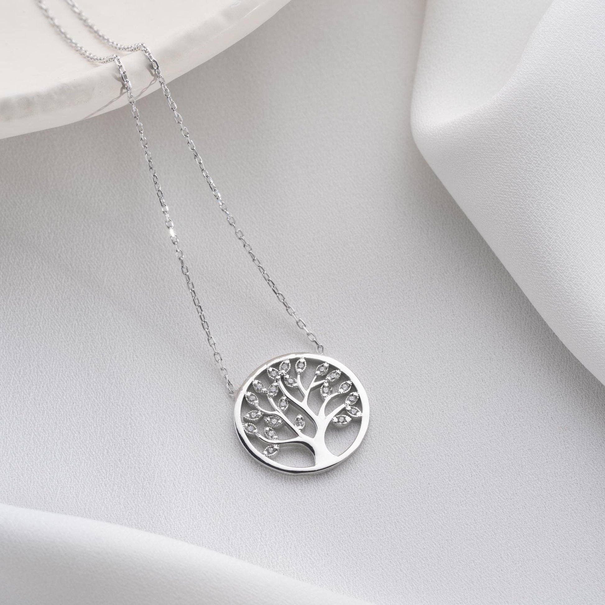 Tree of Life pendant necklace with cubic zirconia stones, available in 925 sterling silver and 14K gold plated options, displayed on a white satin background