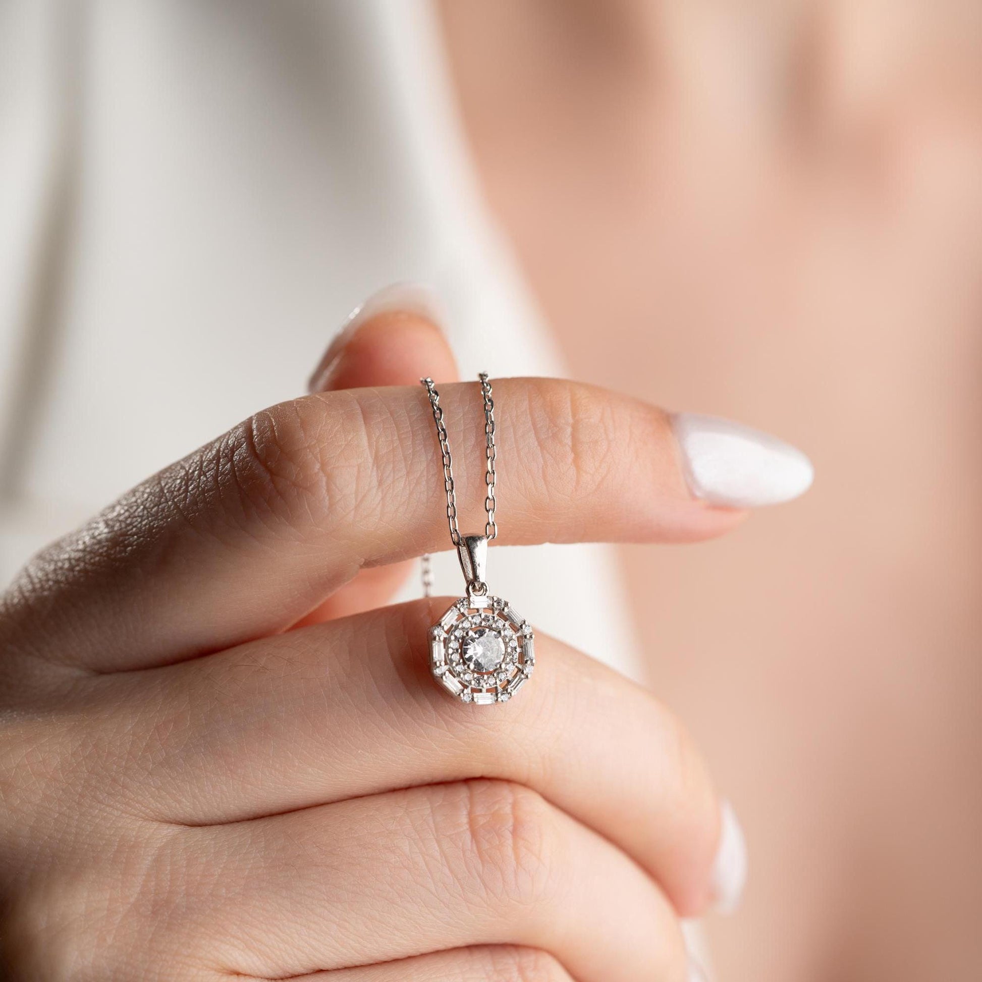 Halo pendant necklace with cubic zirconia stones, available in 925 sterling silver and 14K gold plated options, displayed on a white satin background.