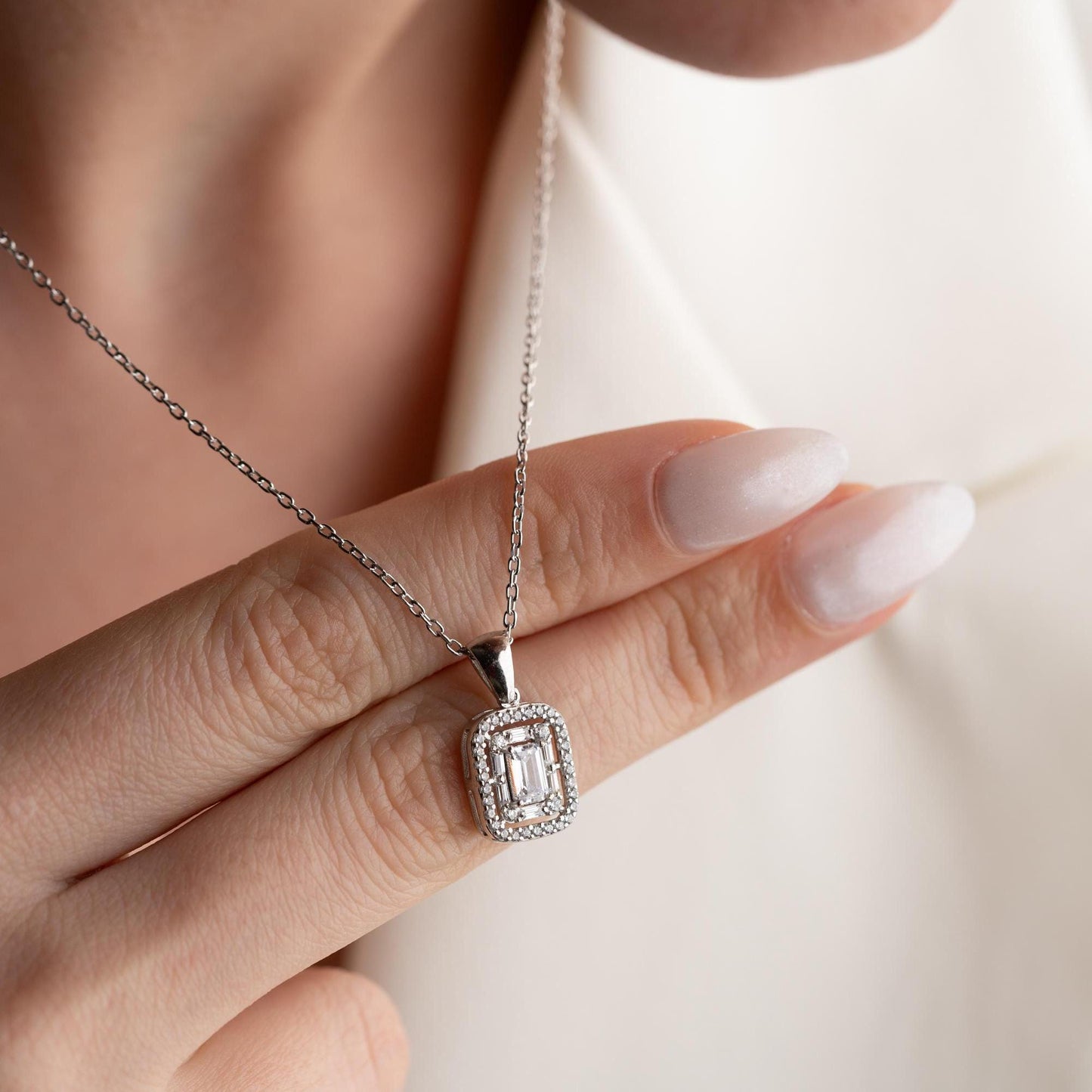 Square baguette pendant necklace with cubic zirconia stones, available in 925 sterling silver and 14K gold plated options, displayed on a white satin background.