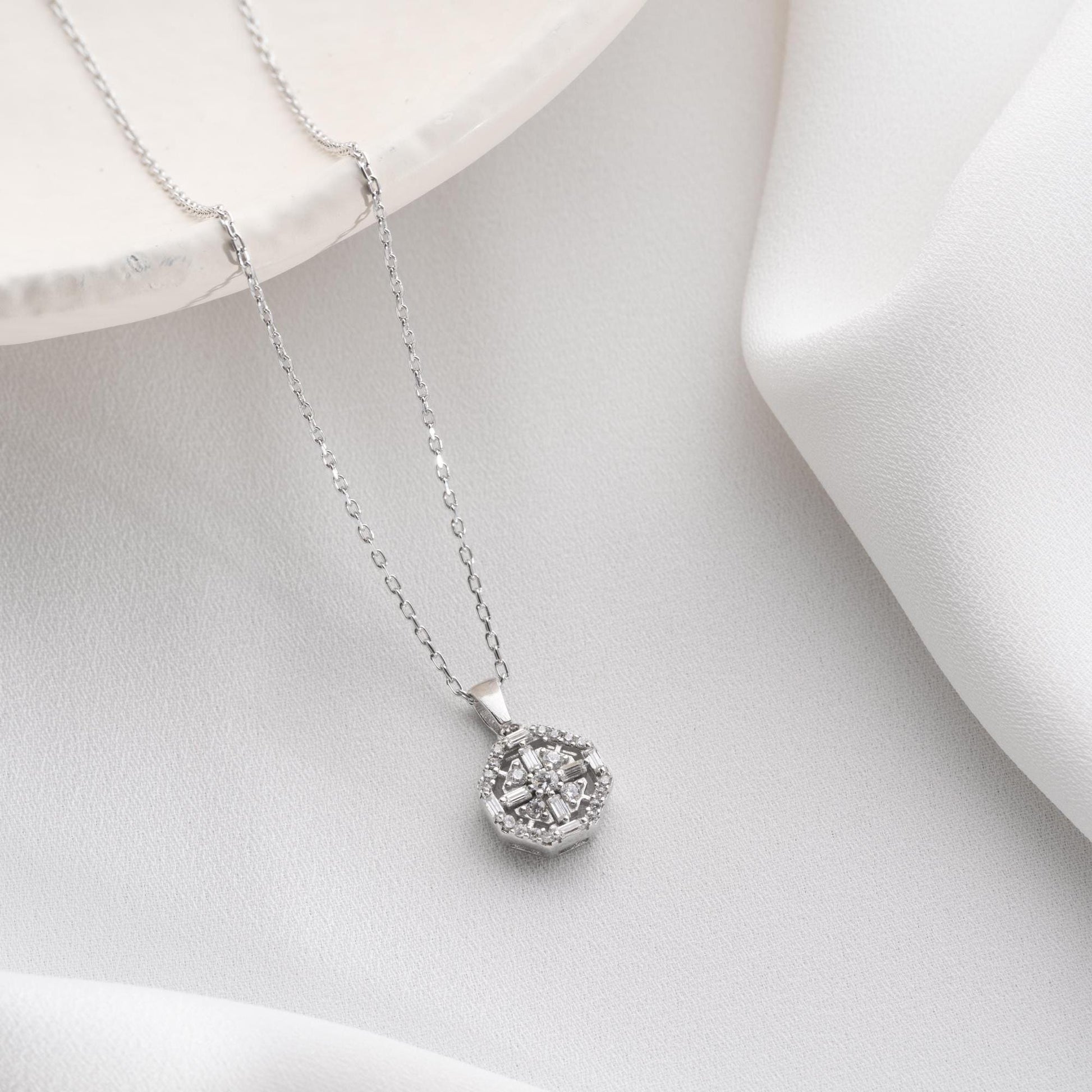 Octagon pendant necklace with cubic zirconia stones, available in 925 sterling silver and 14K gold plated options, displayed on a white satin background