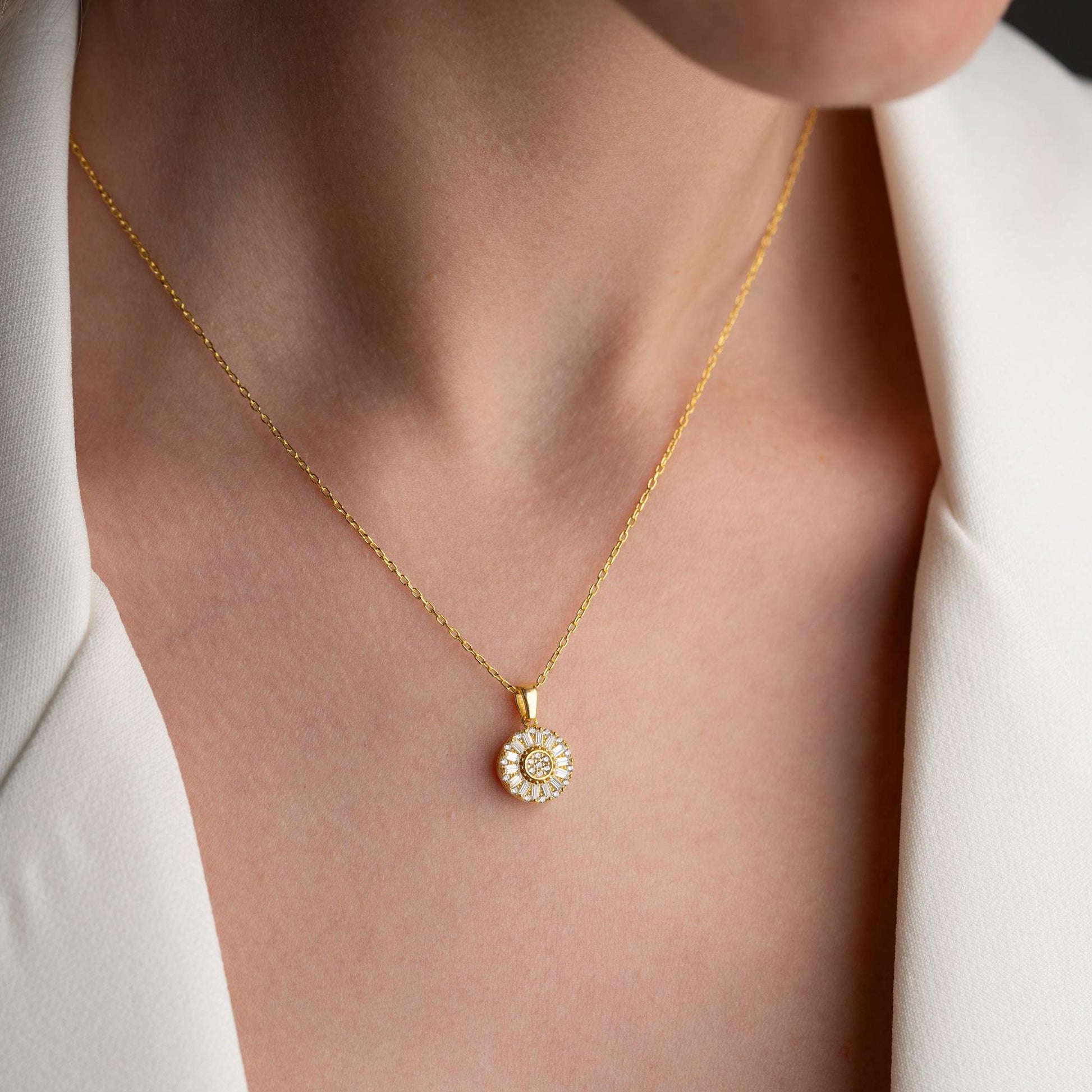 Sunburst pendant necklace with cubic zirconia, available in 925 sterling silver and 14K gold plated options, displayed on a soft satin background