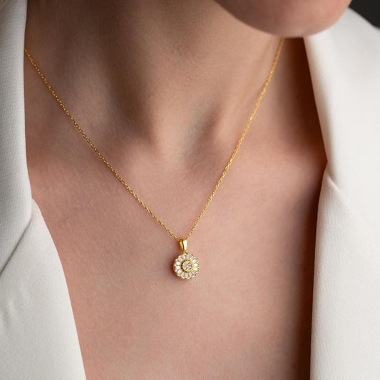 Sunburst pendant necklace with cubic zirconia, available in 925 sterling silver and 14K gold plated options, displayed on a soft satin background