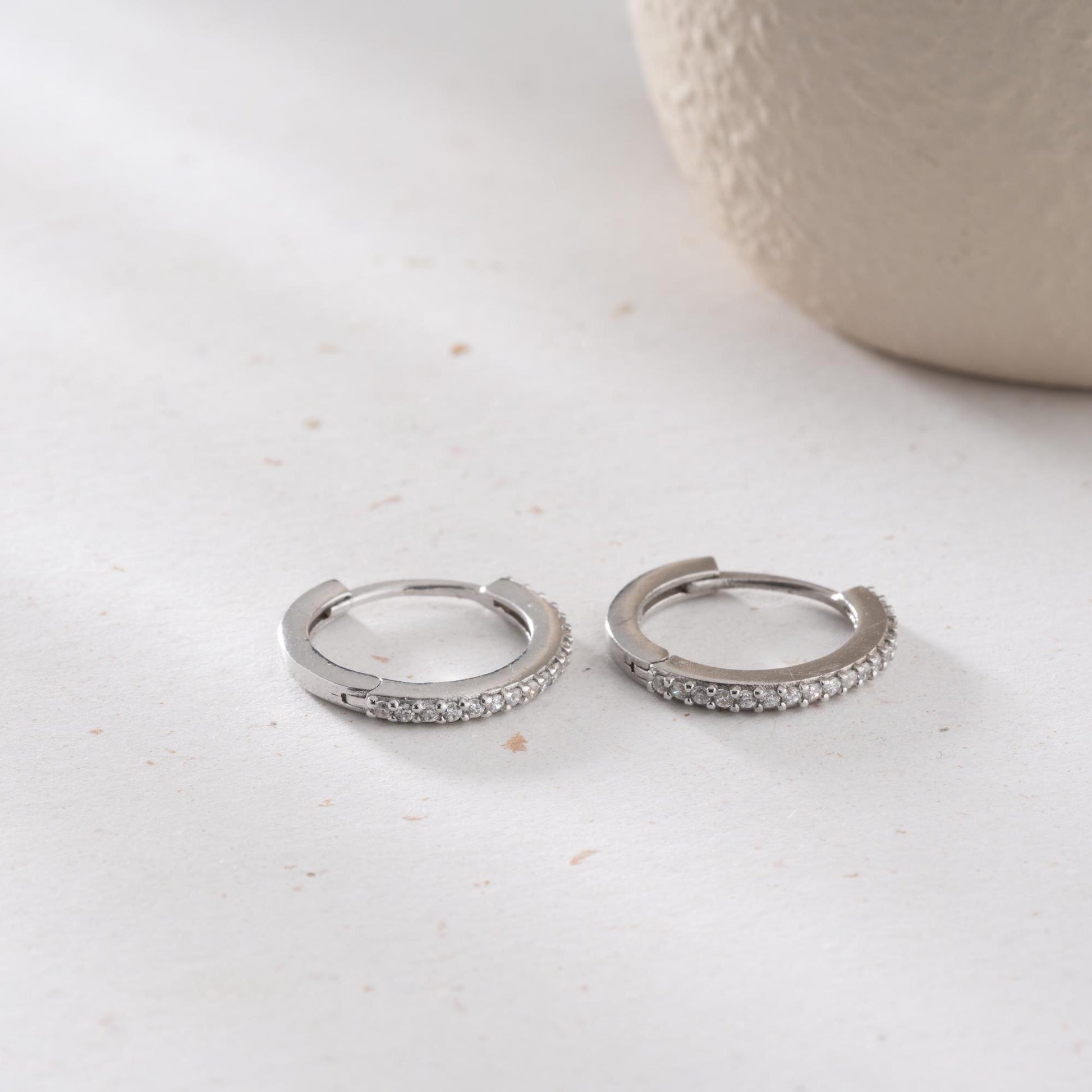 Minimalist hoop earrings with cubic zirconia stones in 925 sterling silver and 14K gold plated options, displayed on a neutral background.