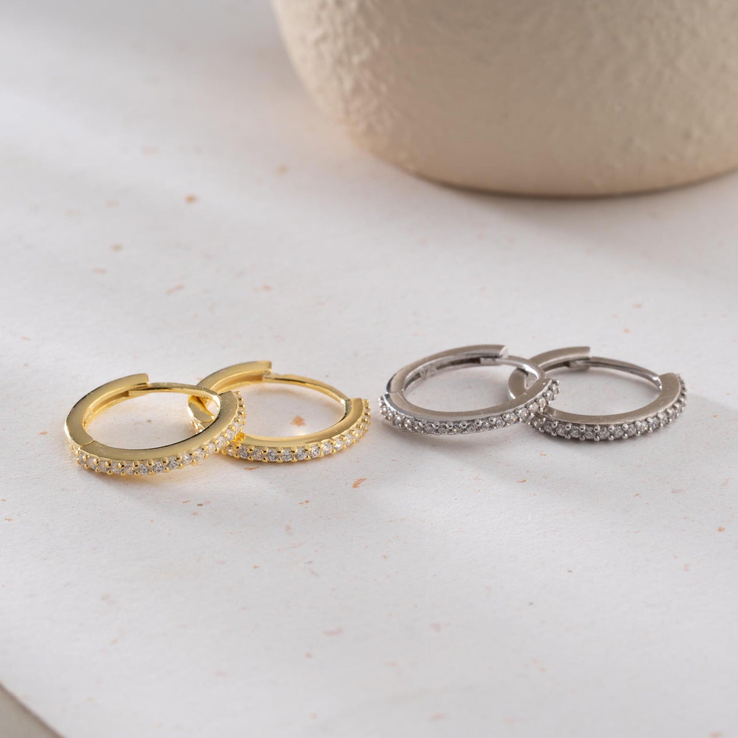 Minimalist hoop earrings with cubic zirconia stones in 925 sterling silver and 14K gold plated options, displayed on a neutral background.