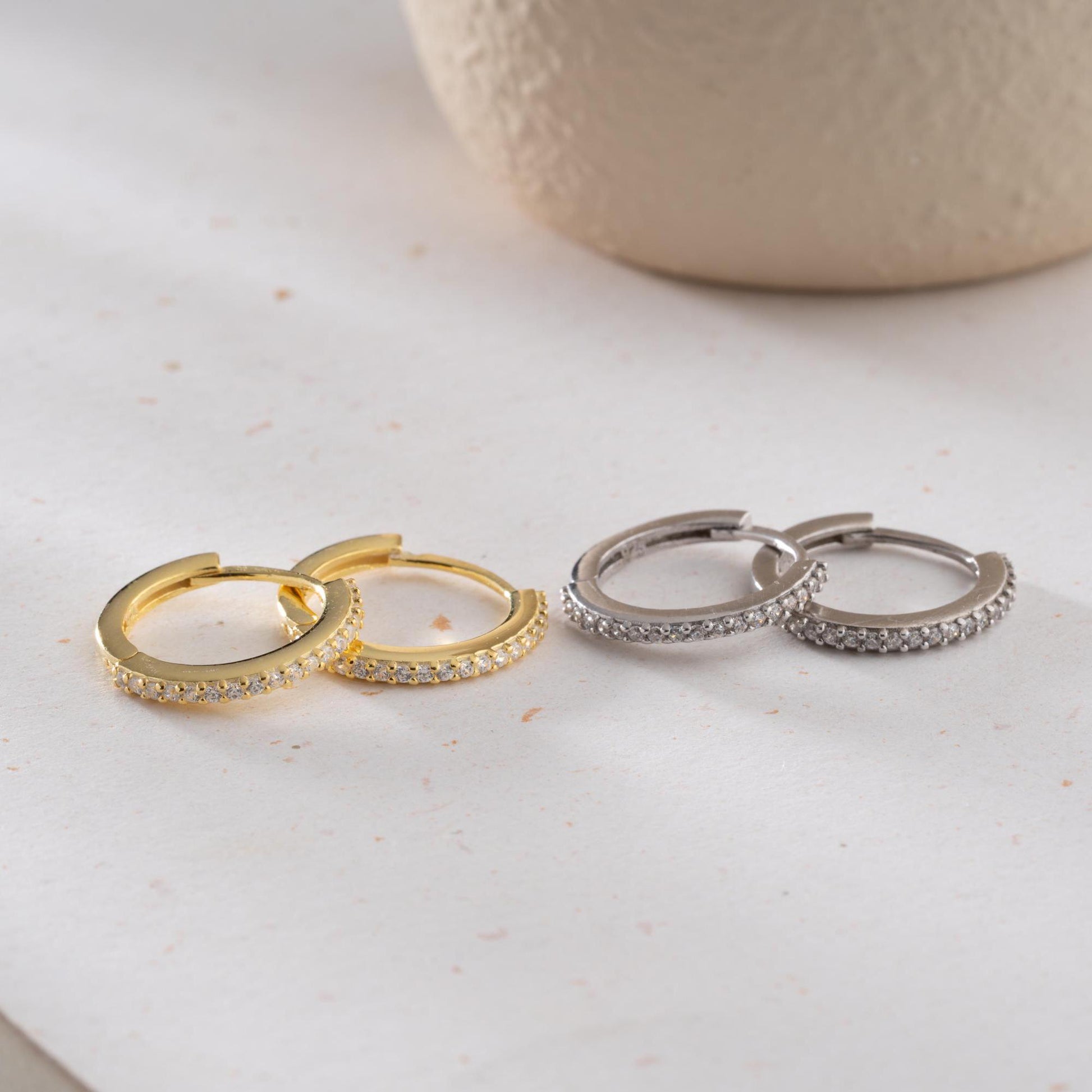 Minimalist hoop earrings with cubic zirconia stones in 925 sterling silver and 14K gold plated options, displayed on a neutral background.