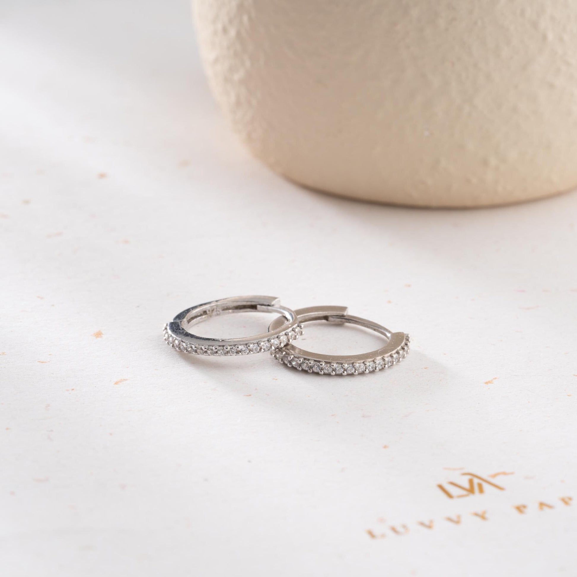 Minimalist hoop earrings with cubic zirconia stones in 925 sterling silver and 14K gold plated options, displayed on a neutral background.