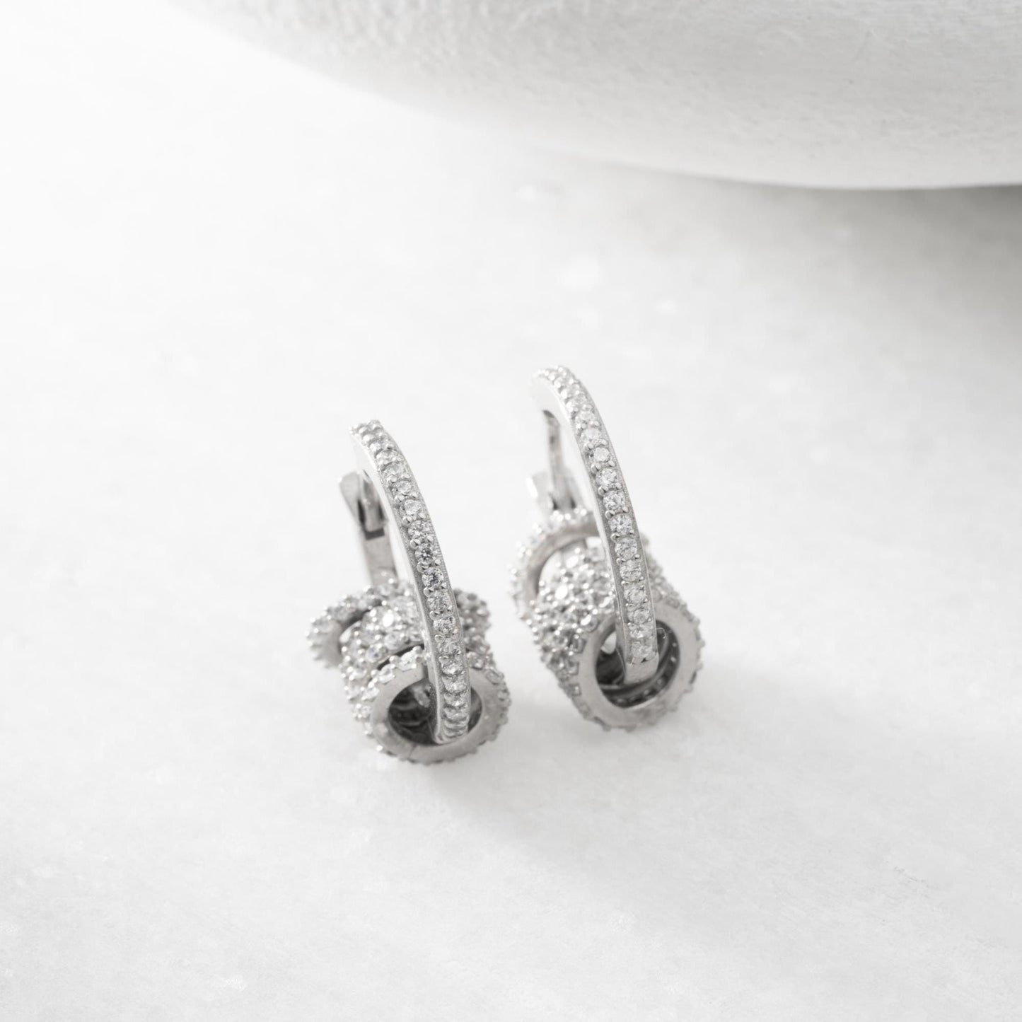 Multi-ring hoop earrings with sparkling cubic zirconia stones in 925 sterling silver and 14K gold-plated options, displayed on a marble background.