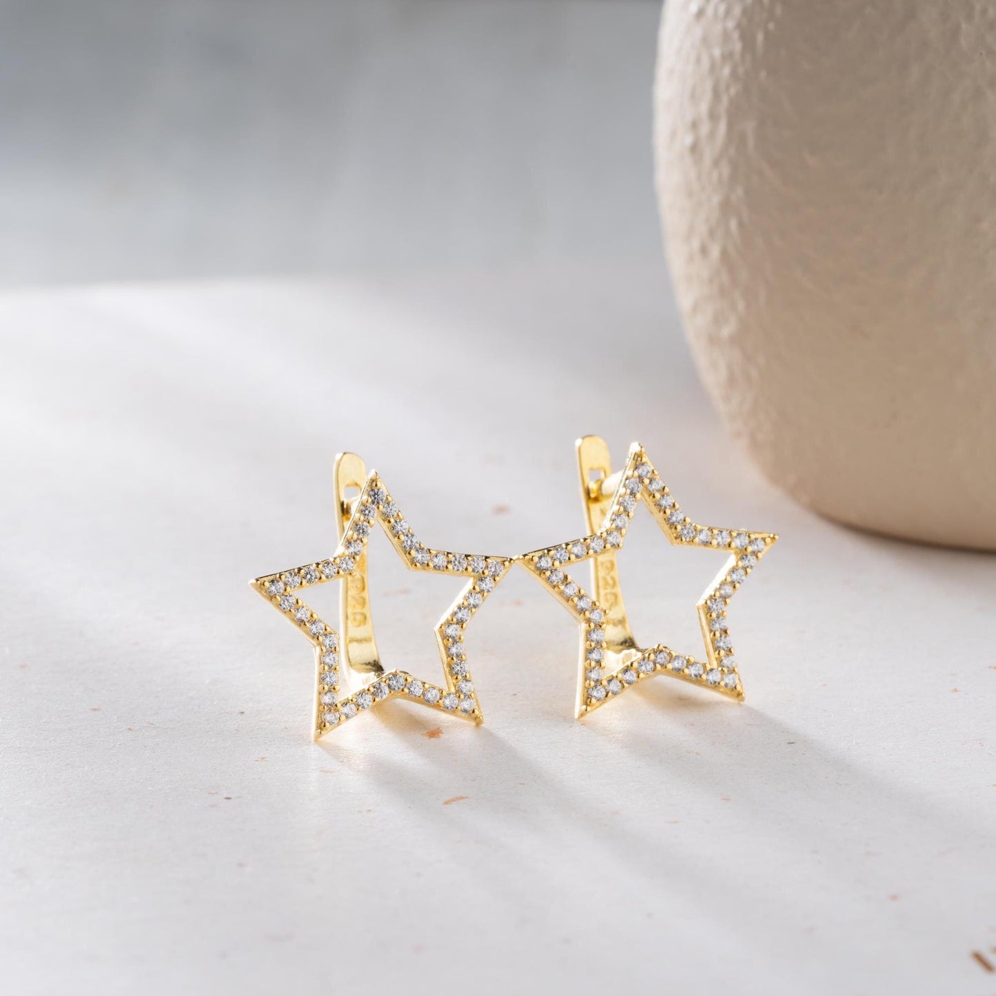 Star-shaped earrings with cubic zirconia stones, available in 925 sterling silver and 14K gold plated options, displayed on a minimalist background.