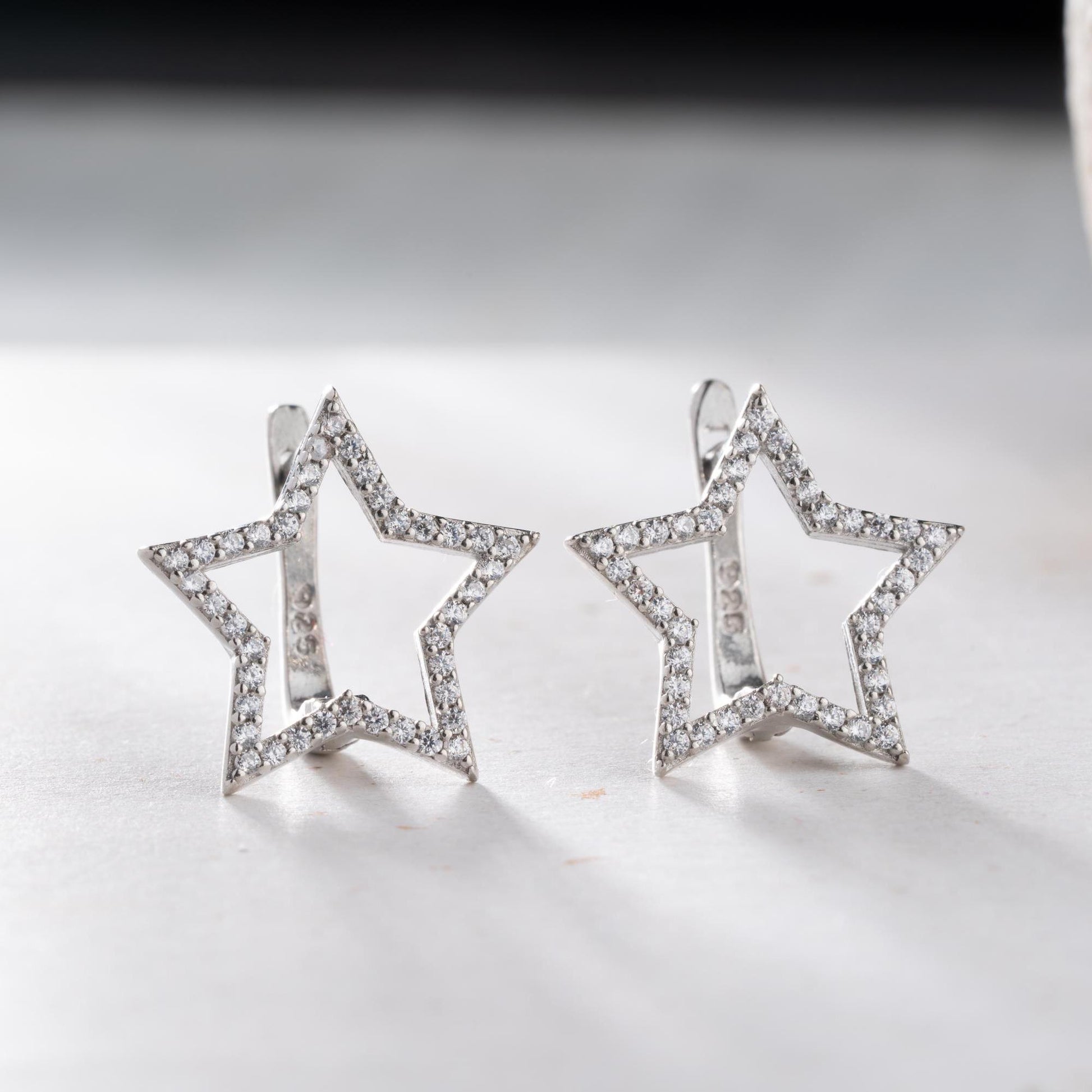Star-shaped earrings with cubic zirconia stones, available in 925 sterling silver and 14K gold plated options, displayed on a minimalist background.
