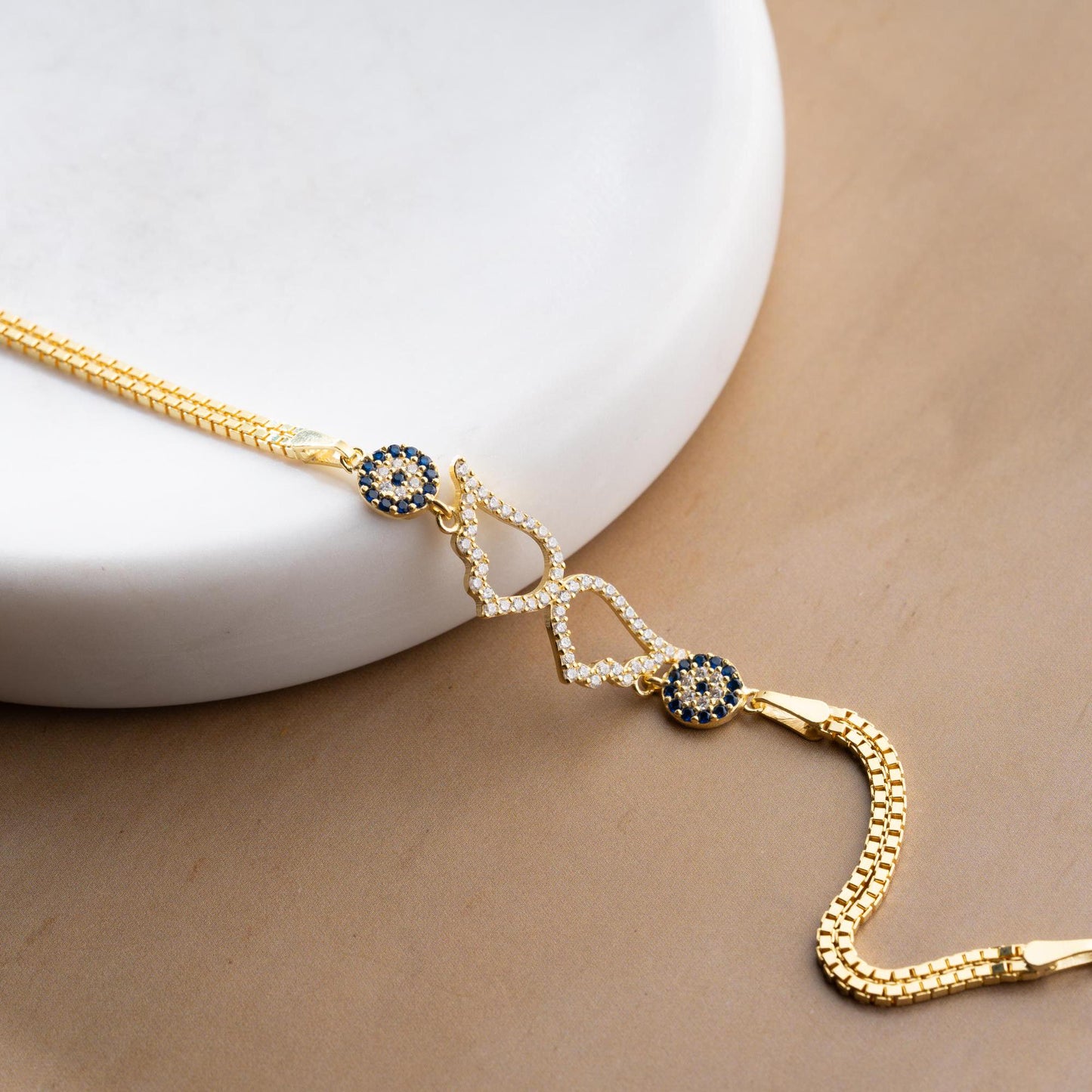 A luxurious Turkish-inspired evil eye and angel wing charm bracelet crafted in 925 sterling silver with sparkling cubic zirconia stones, available in gold and silver options.