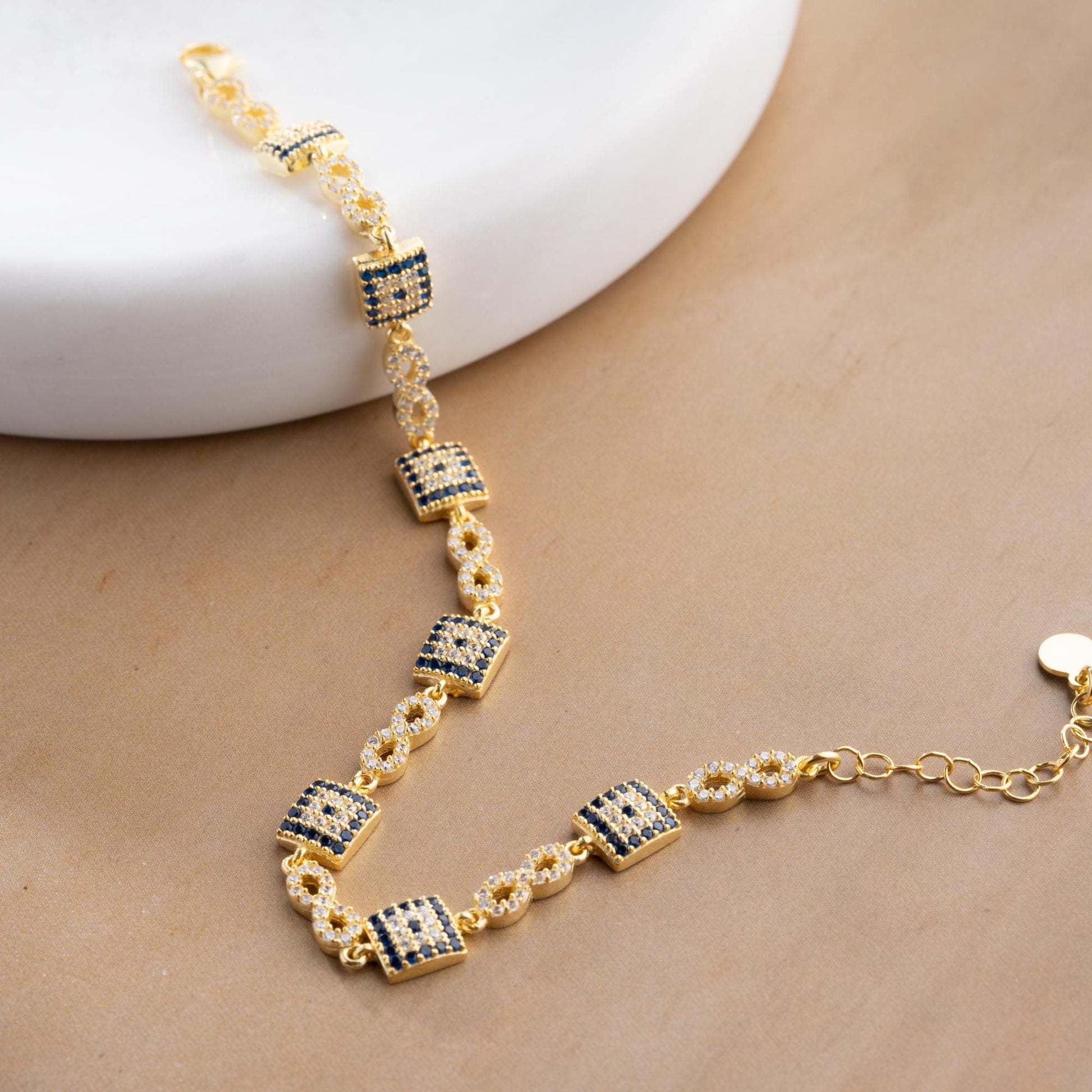 Elegant charm bracelet featuring square evil eye motifs and infinity symbols, crafted in 925 Sterling Silver with cubic zirconia stones, available in silver and gold finishes, perfect for festive gifting.
