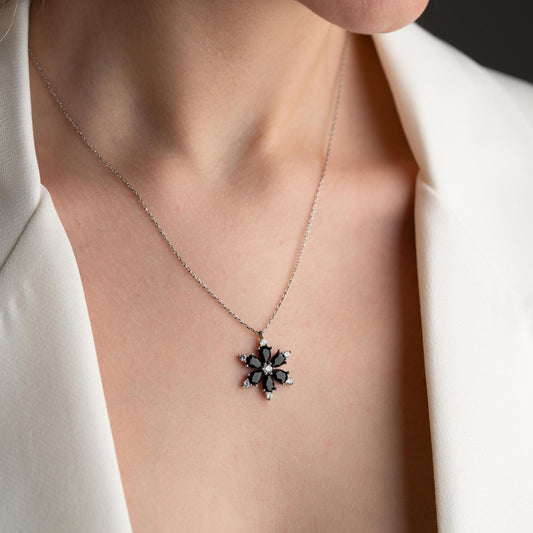 Elegant black flower necklace with genuine zircon stones, available in 925 sterling silver and 14K gold plated options, displayed on a white satin background.