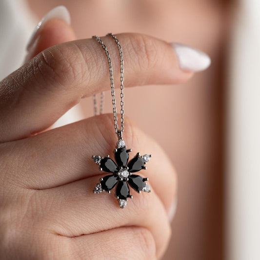 Elegant black flower necklace with genuine zircon stones, available in 925 sterling silver and 14K gold plated options, displayed on a white satin background.