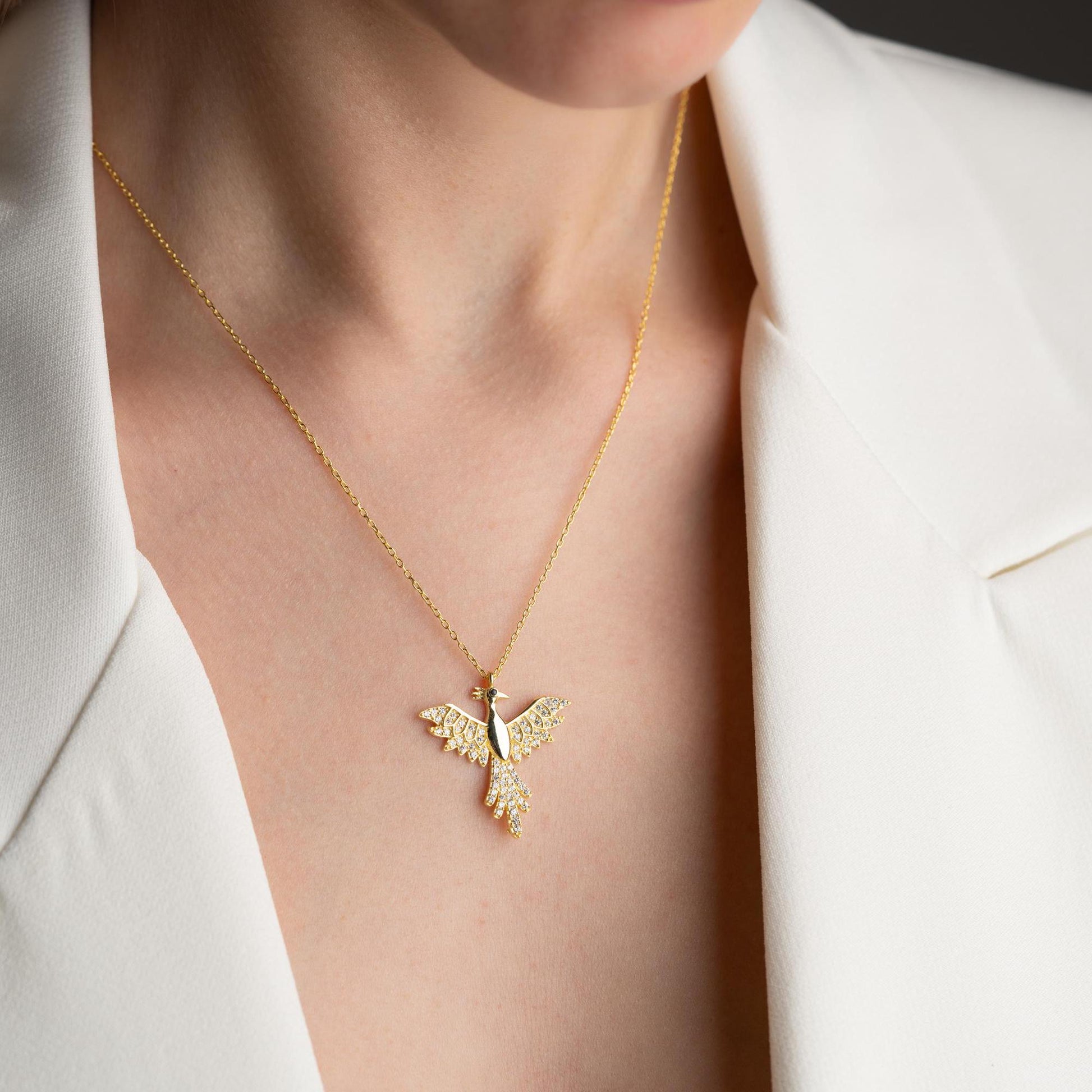Elegant bird-shaped necklace with cubic zirconia stones, available in 925 sterling silver and 14K gold plated options, displayed on a white satin background.