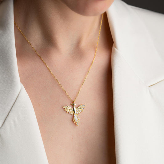 Elegant bird-shaped necklace with cubic zirconia stones, available in 925 sterling silver and 14K gold plated options, displayed on a white satin background.