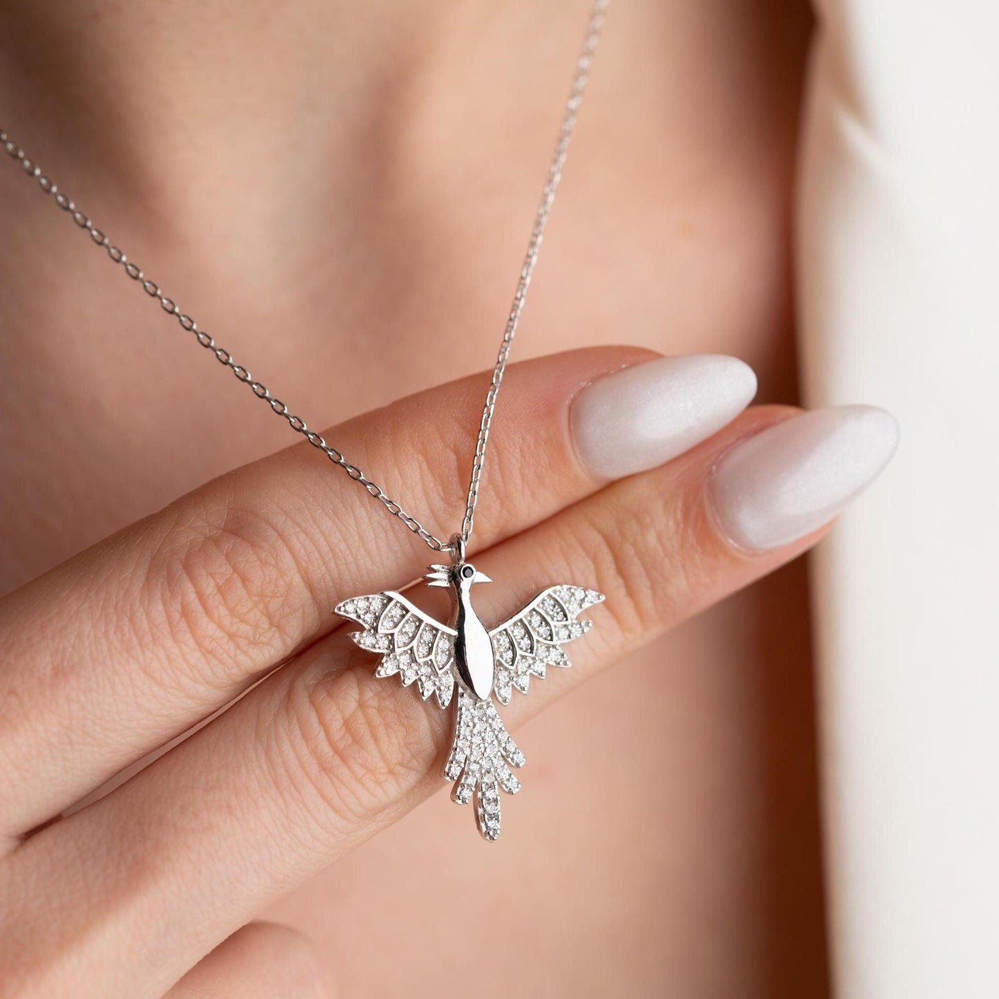 Elegant bird-shaped necklace with cubic zirconia stones, available in 925 sterling silver and 14K gold plated options, displayed on a white satin background.