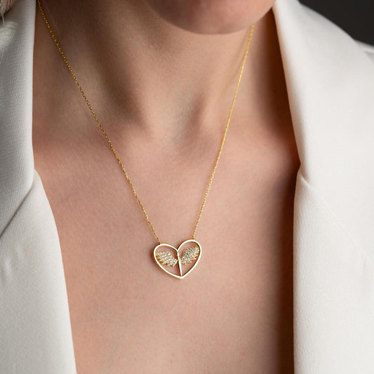 Angel wing heart necklace with cubic zirconia stones, available in 925 sterling silver and 14K gold plated options, displayed on a white satin background