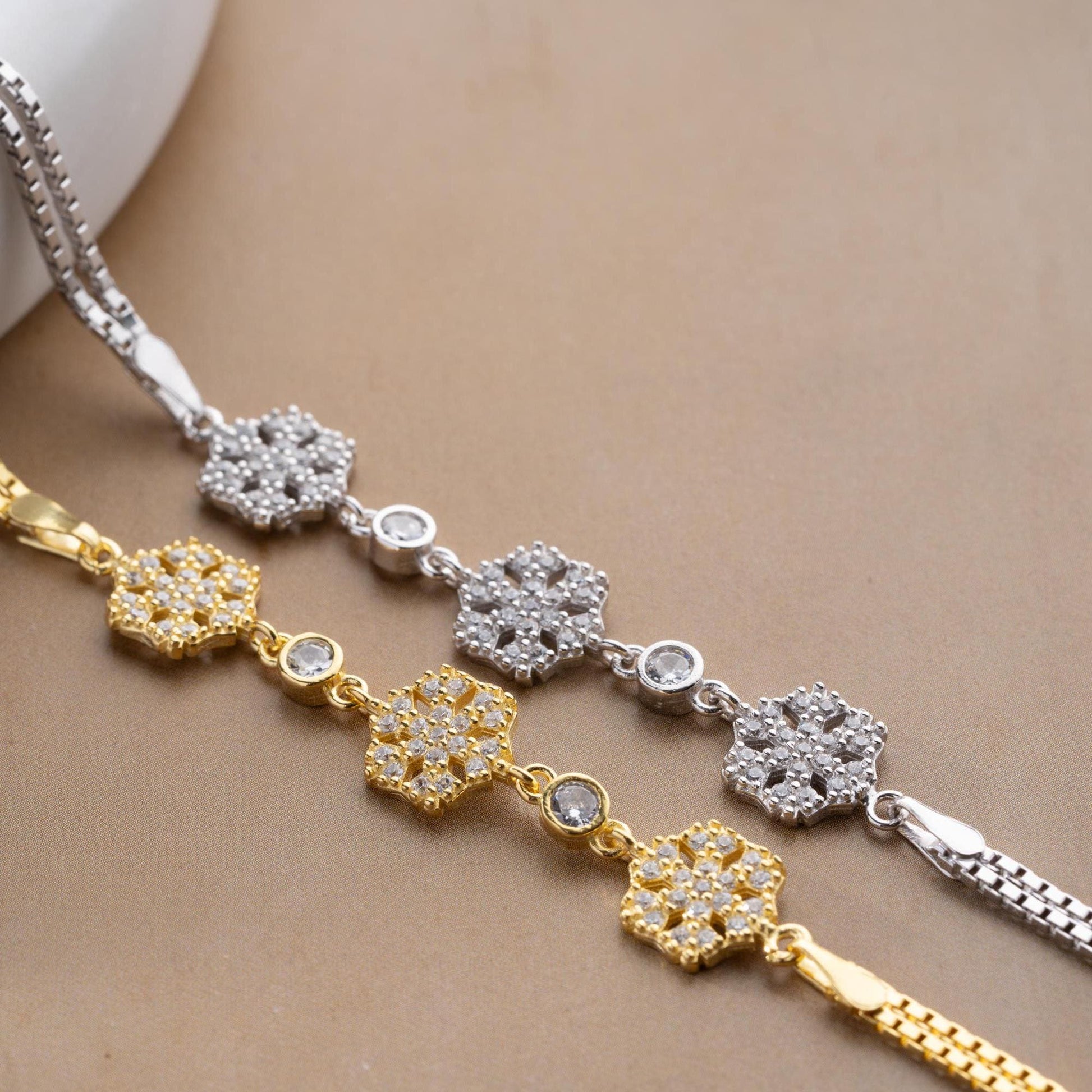 Elegant snowflake charm bracelet crafted in 925 Sterling Silver with cubic zirconia stones, available in silver and gold finishes, perfect for winter gifting.