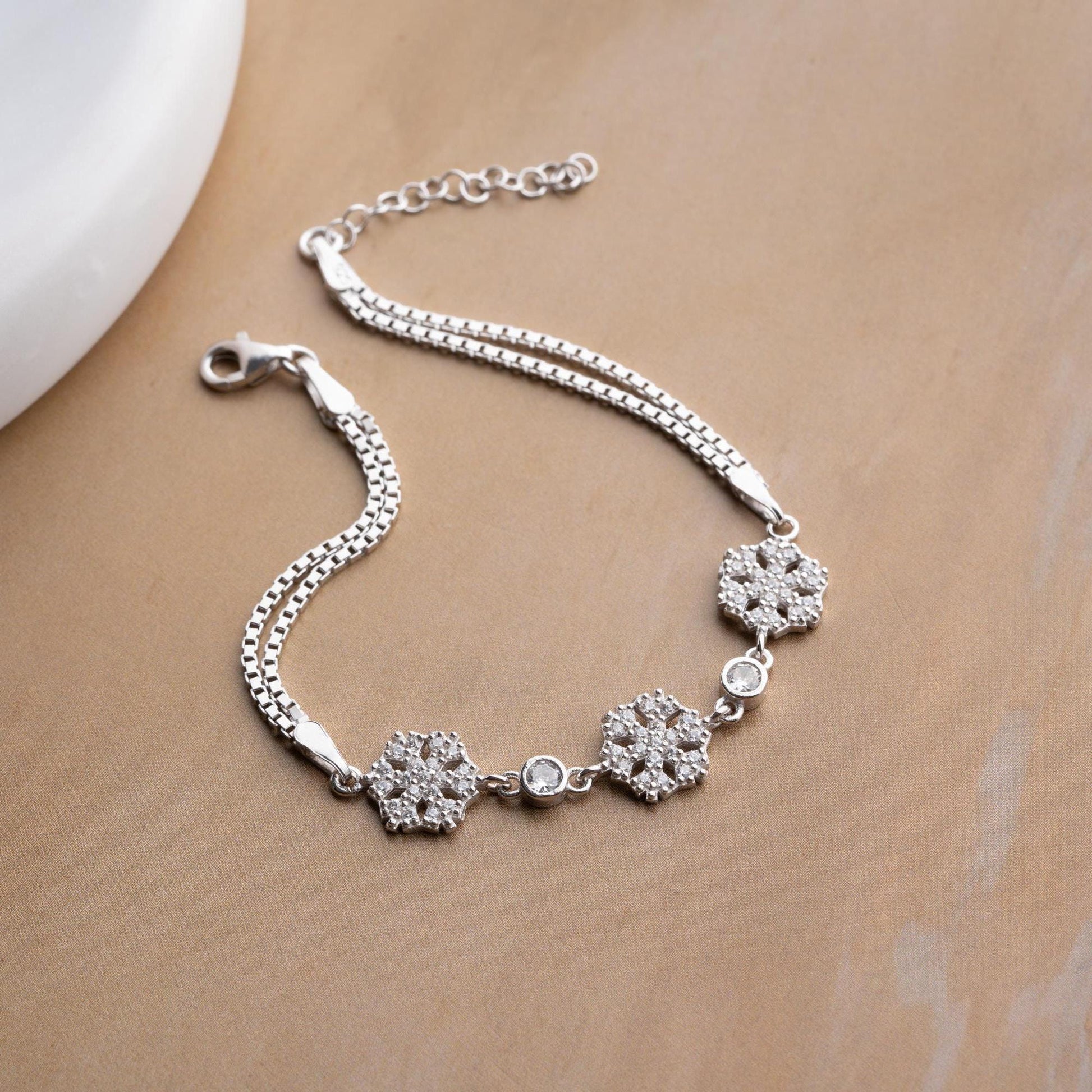 Elegant snowflake charm bracelet crafted in 925 Sterling Silver with cubic zirconia stones, available in silver and gold finishes, perfect for winter gifting.