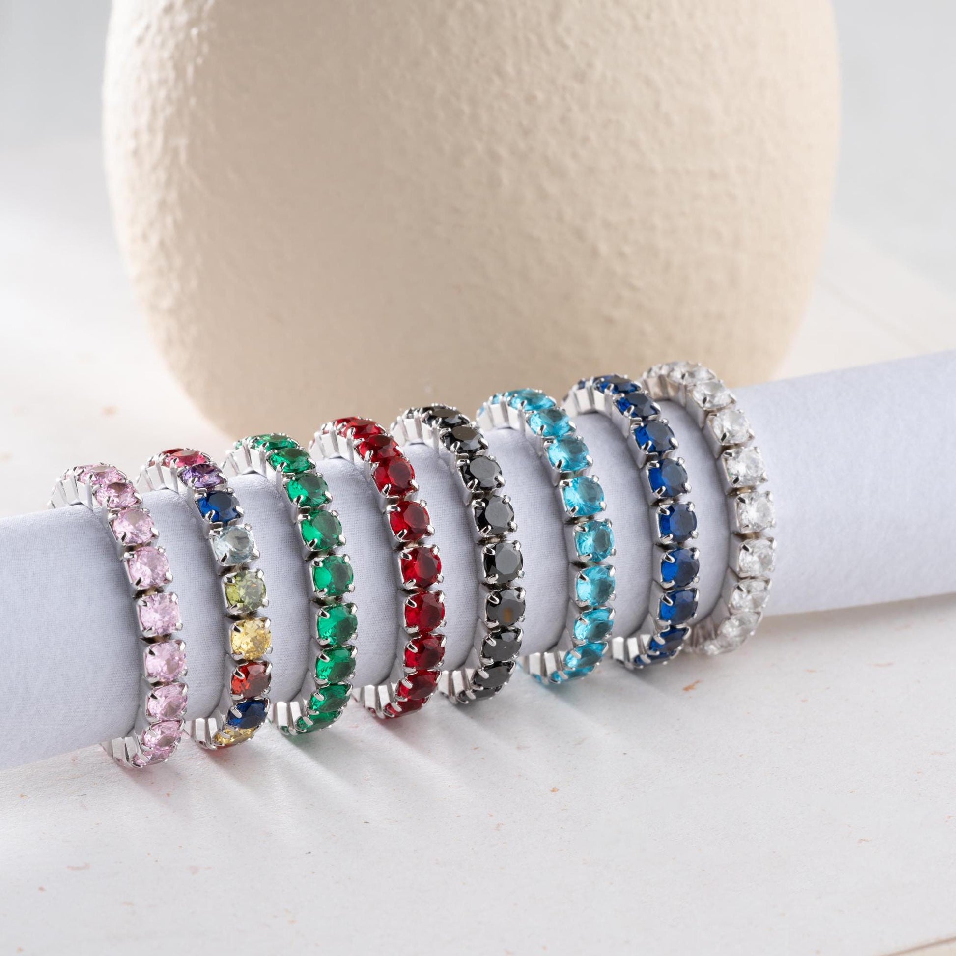 Single vibrant tennis ring crafted in 925 Sterling Silver with colorful cubic zirconia stones, available in rainbow, red, blue, green, black, and pink.