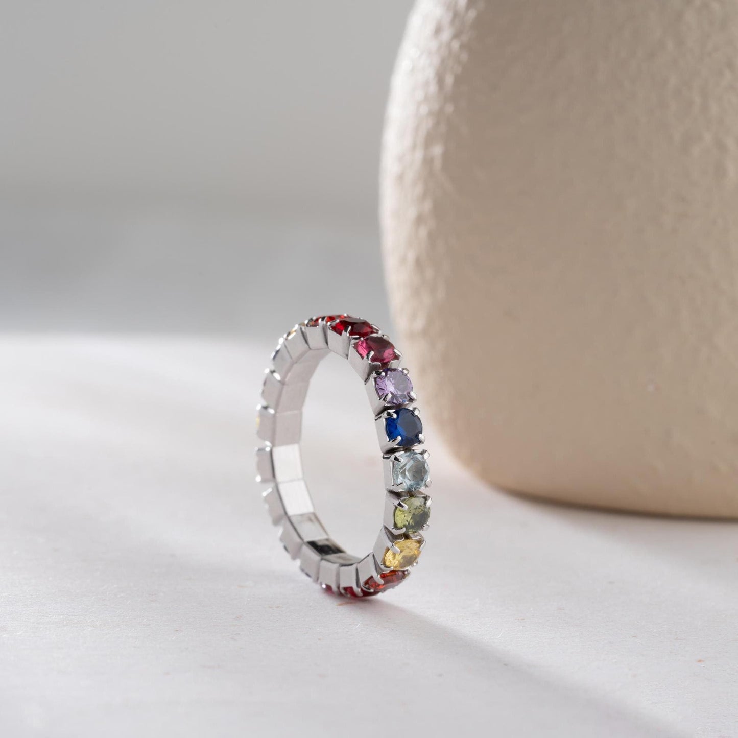 Single vibrant tennis ring crafted in 925 Sterling Silver with colorful cubic zirconia stones, available in rainbow, red, blue, green, black, and pink.