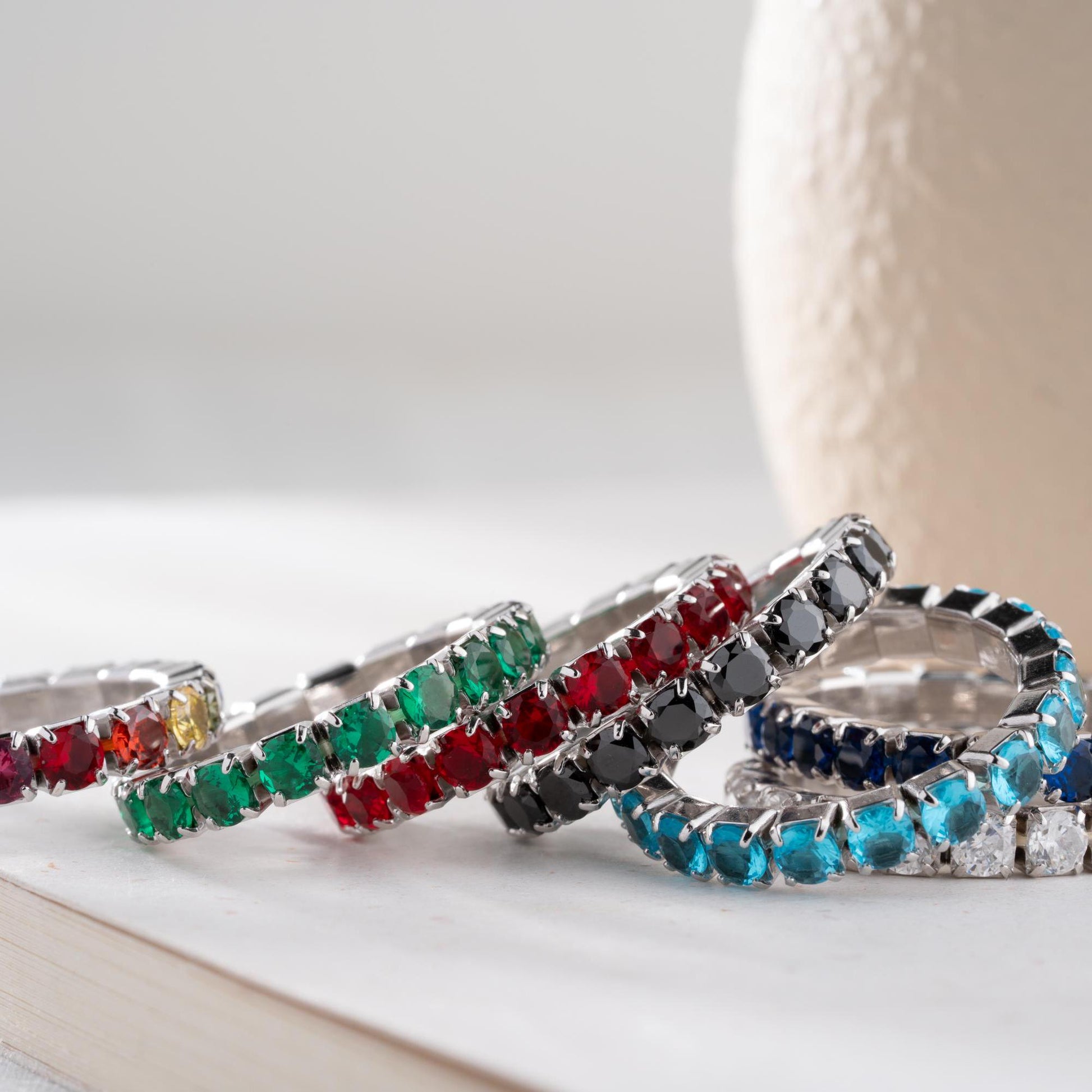Single vibrant tennis ring crafted in 925 Sterling Silver with colorful cubic zirconia stones, available in rainbow, red, blue, green, black, and pink.
