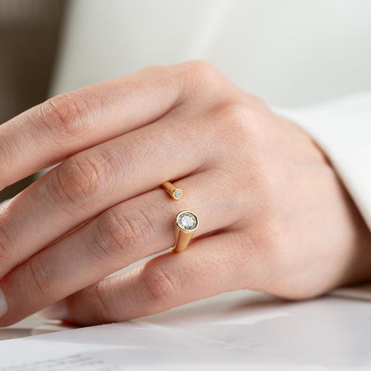 Elegant open ring with dual bezel-set zircon stones, crafted from 925 sterling silver and available in gold plated and silver finishes.