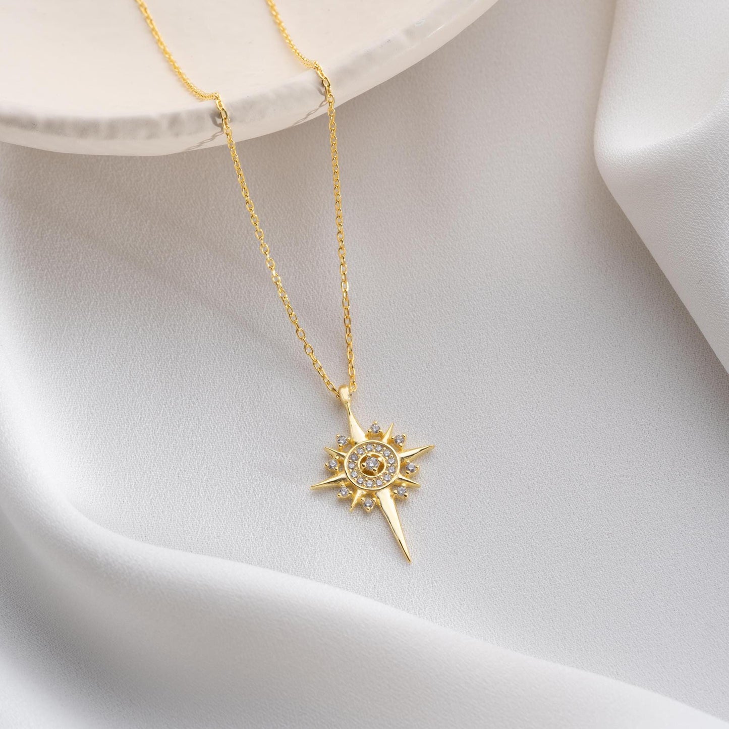 Sun and star necklace with cubic zirconia stones, available in 925 sterling silver and 14K gold plated options, displayed on a white satin background.
