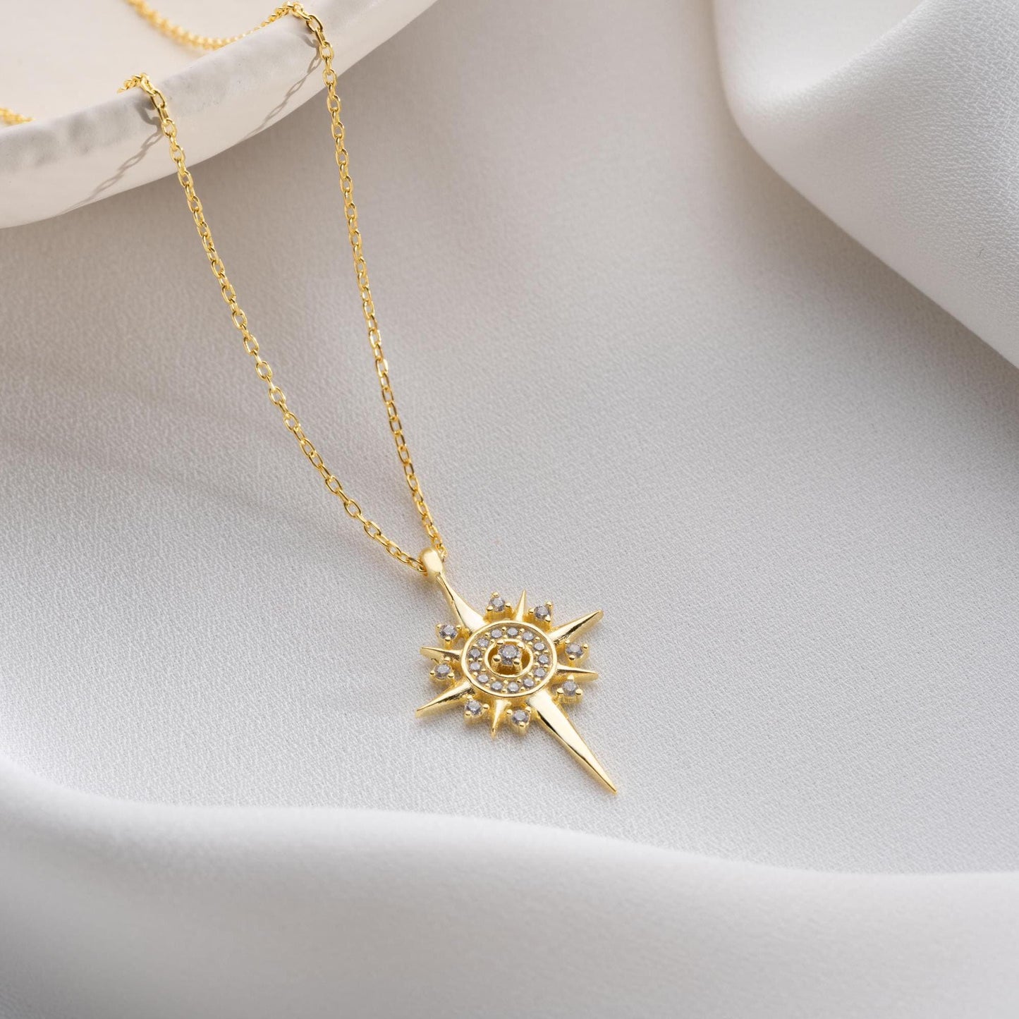 Sun and star necklace with cubic zirconia stones, available in 925 sterling silver and 14K gold plated options, displayed on a white satin background.