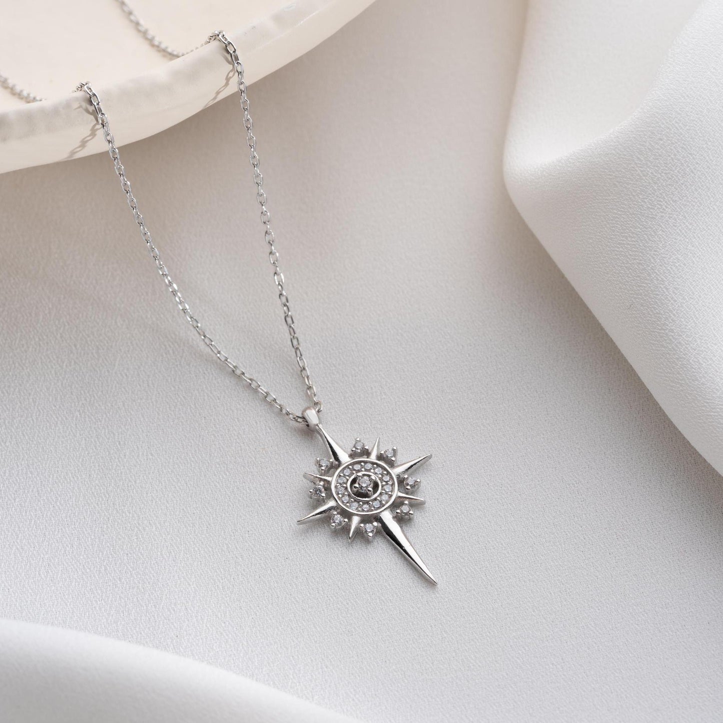 Sun and star necklace with cubic zirconia stones, available in 925 sterling silver and 14K gold plated options, displayed on a white satin background.