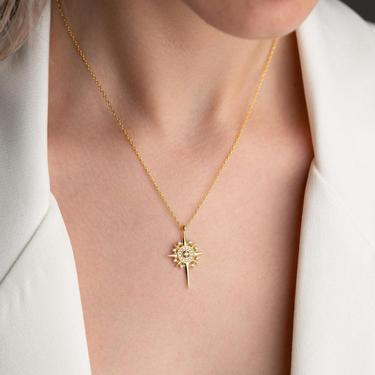 Sun and star necklace with cubic zirconia stones, available in 925 sterling silver and 14K gold plated options, displayed on a white satin background.