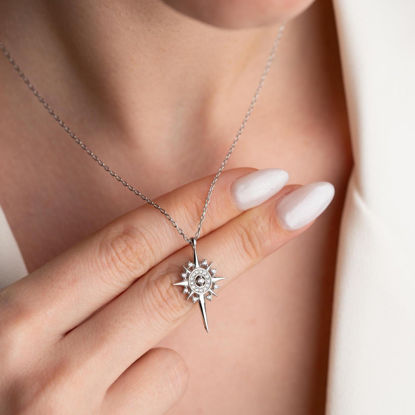 Sun and star necklace with cubic zirconia stones, available in 925 sterling silver and 14K gold plated options, displayed on a white satin background.