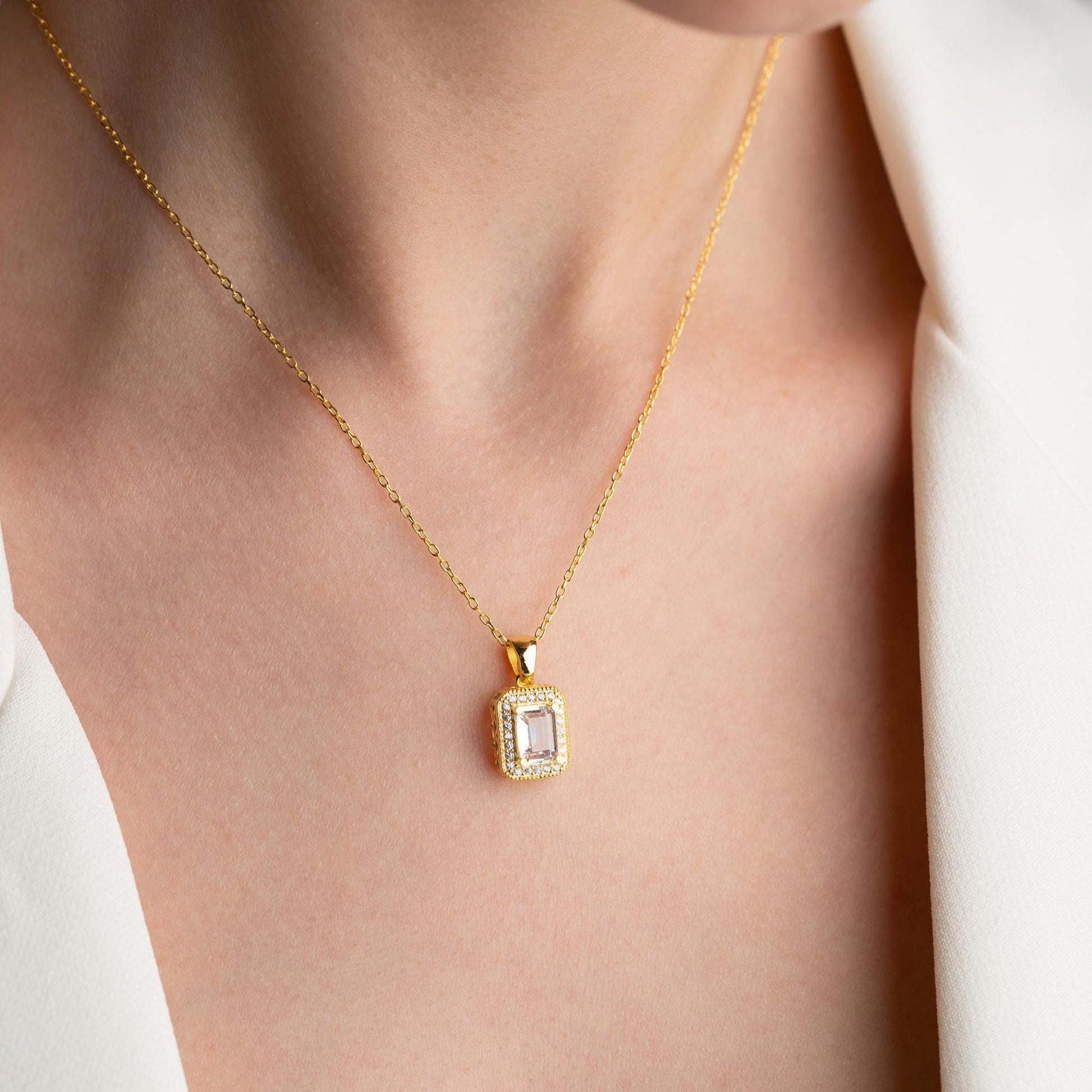 Baguette-cut pendant necklace with cubic zirconia stones, available in 925 sterling silver and 14K gold plated options, displayed on a white satin background
